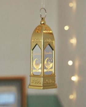 Golden lantern hanging with twinkling lights, symbolizing Ramadan celebration indoors.