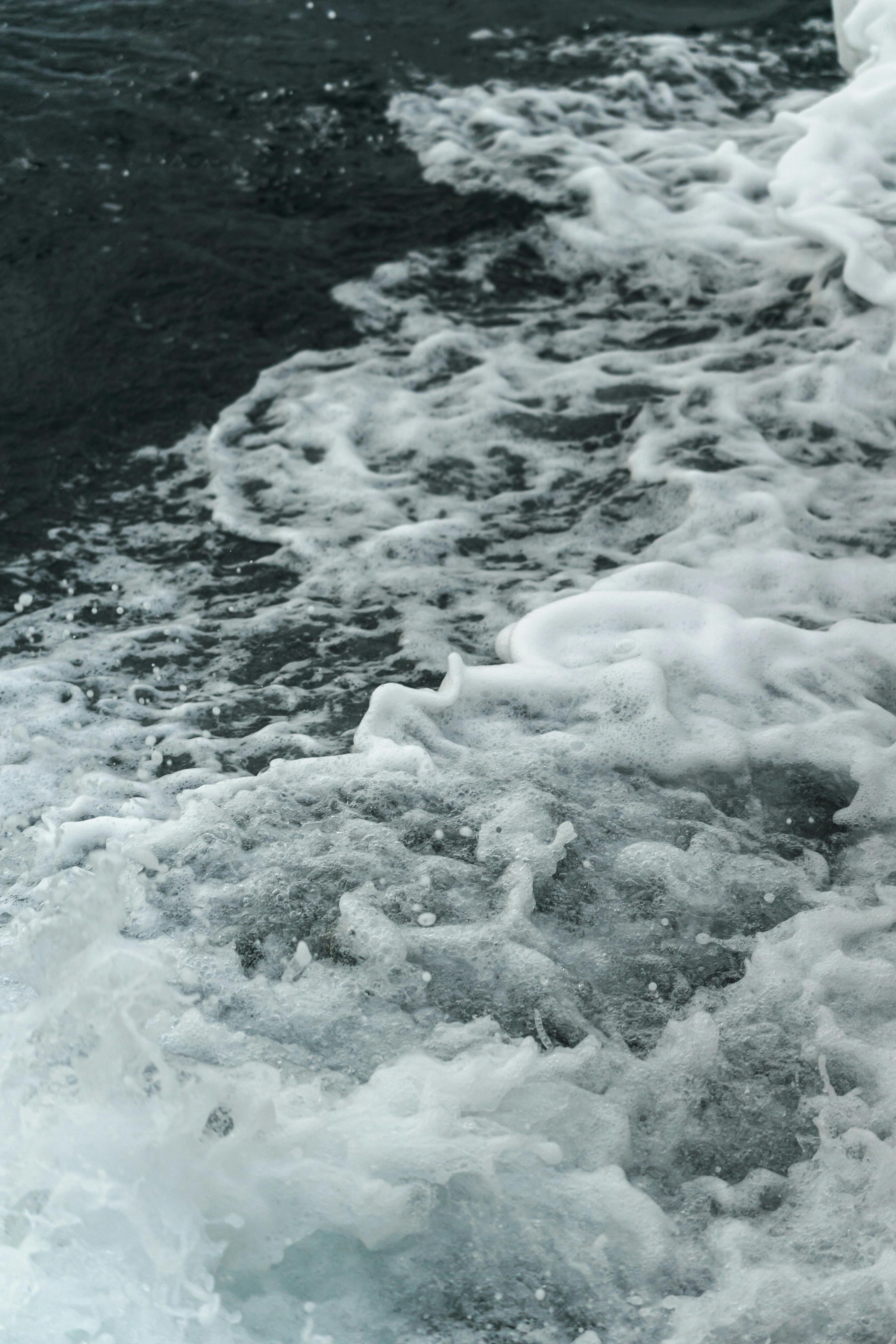 ingyenes Dinamikus óceánhullámok, amelyek fehér habbal csapódnak a sziklás partszakasznak, megragadva a természet erejét. Stockfotó