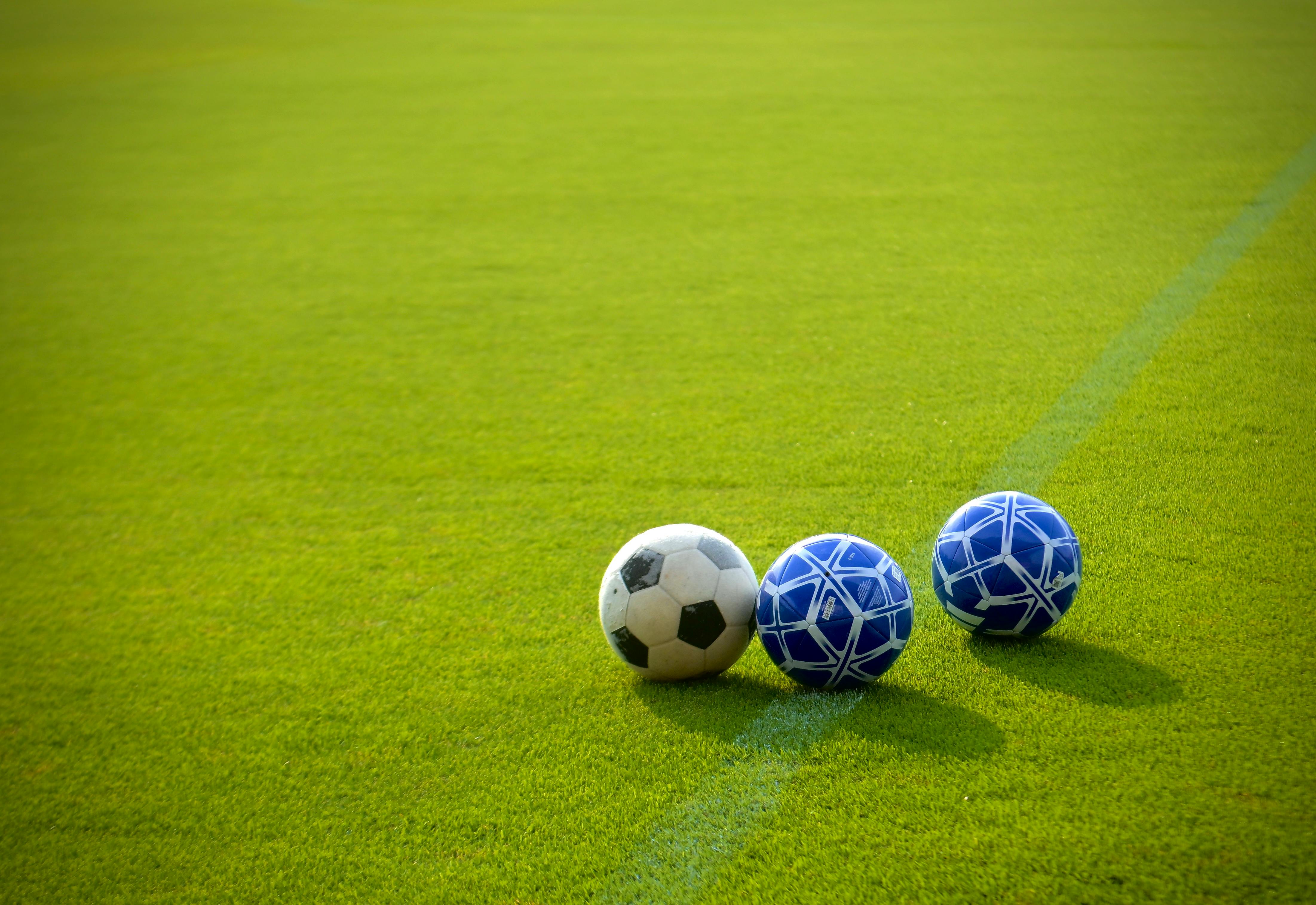 ฟรี ลูกฟุตบอลสามลูกวางอยู่บนสนามหญ้าสีเขียวสดใสท่ามกลางแสงแดดอ่อนๆ ยามบ่าย เหมาะอย่างยิ่งสำหรับธีมกีฬา คลังภาพถ่าย