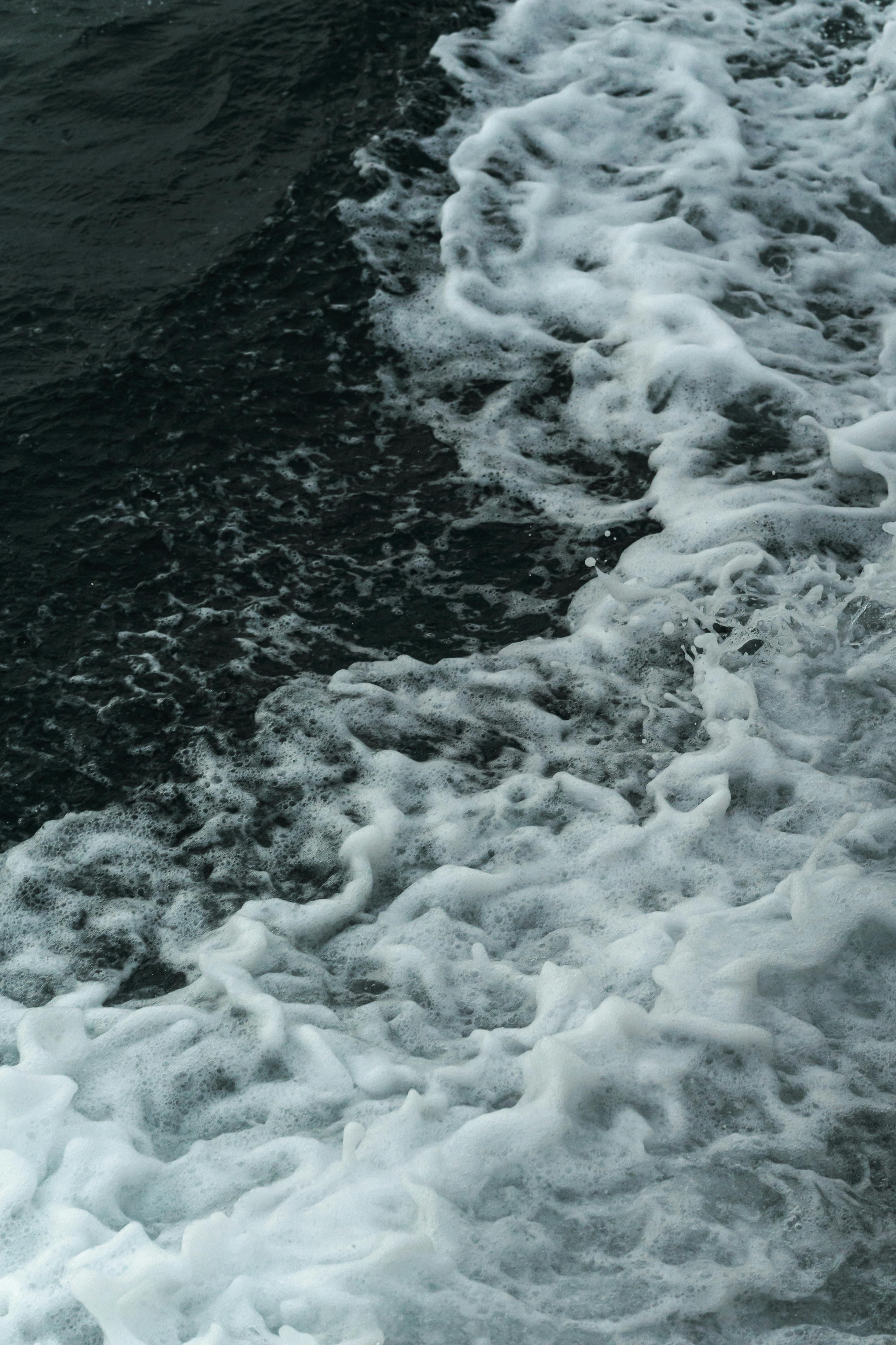 Безкоштовне Крупний план океанських хвиль, що розбиваються об берег, утворюючи пінисту білу піну, демонструючи динамічний рух моря. стокове фото