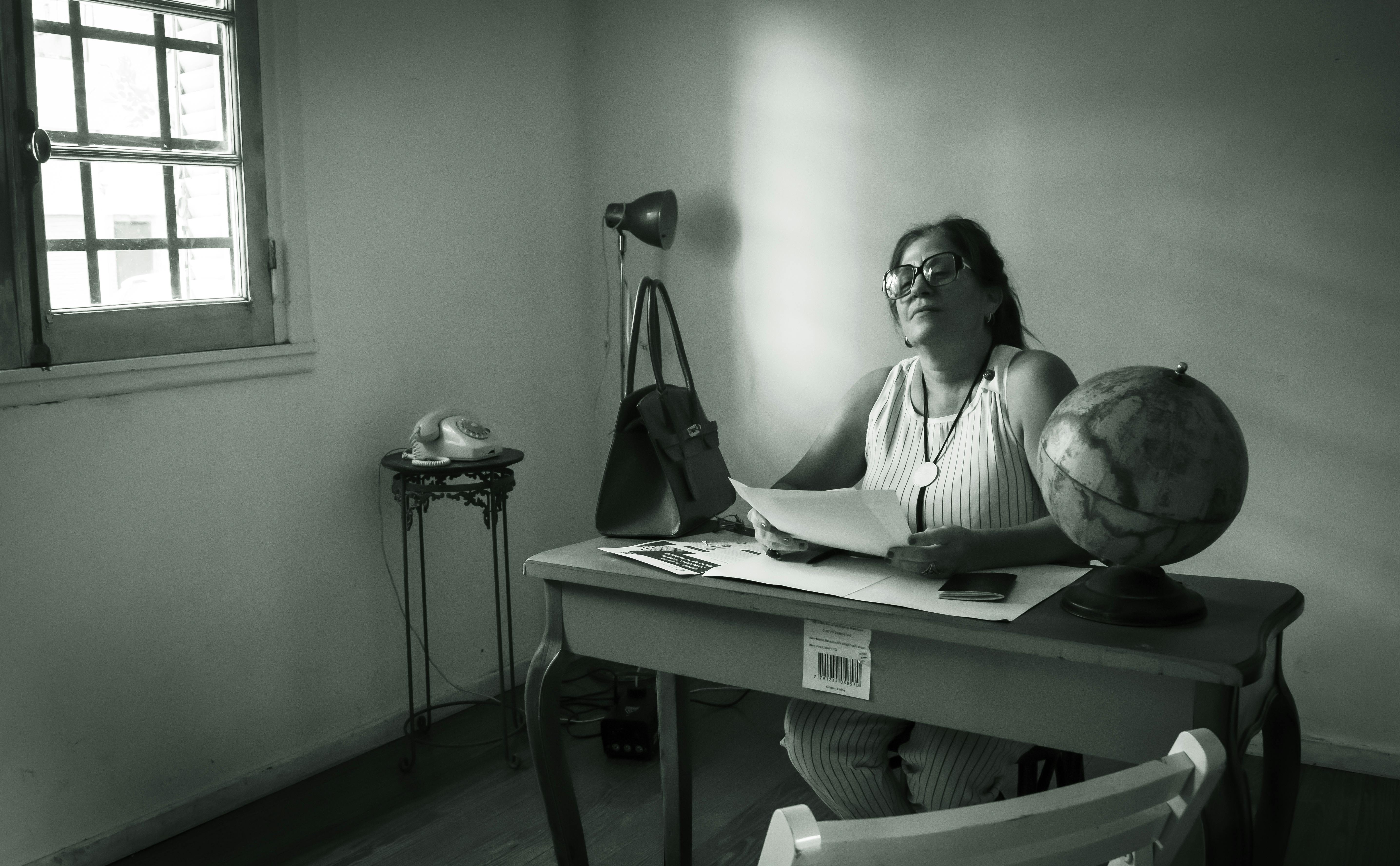 免費 一位女士坐在擺放著復古家具的桌子前，在充滿懷舊氣息的辦公環境中翻閱文件。 圖庫相片