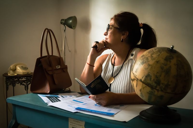 Businesswoman pondering at her desk with a globe, documents, and a lamp. Captures intellectual ambiance.