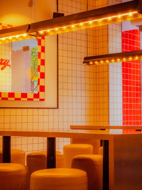Free Warmly lit modern diner interior featuring red and white tiles and cozy seating. Stock Photo
