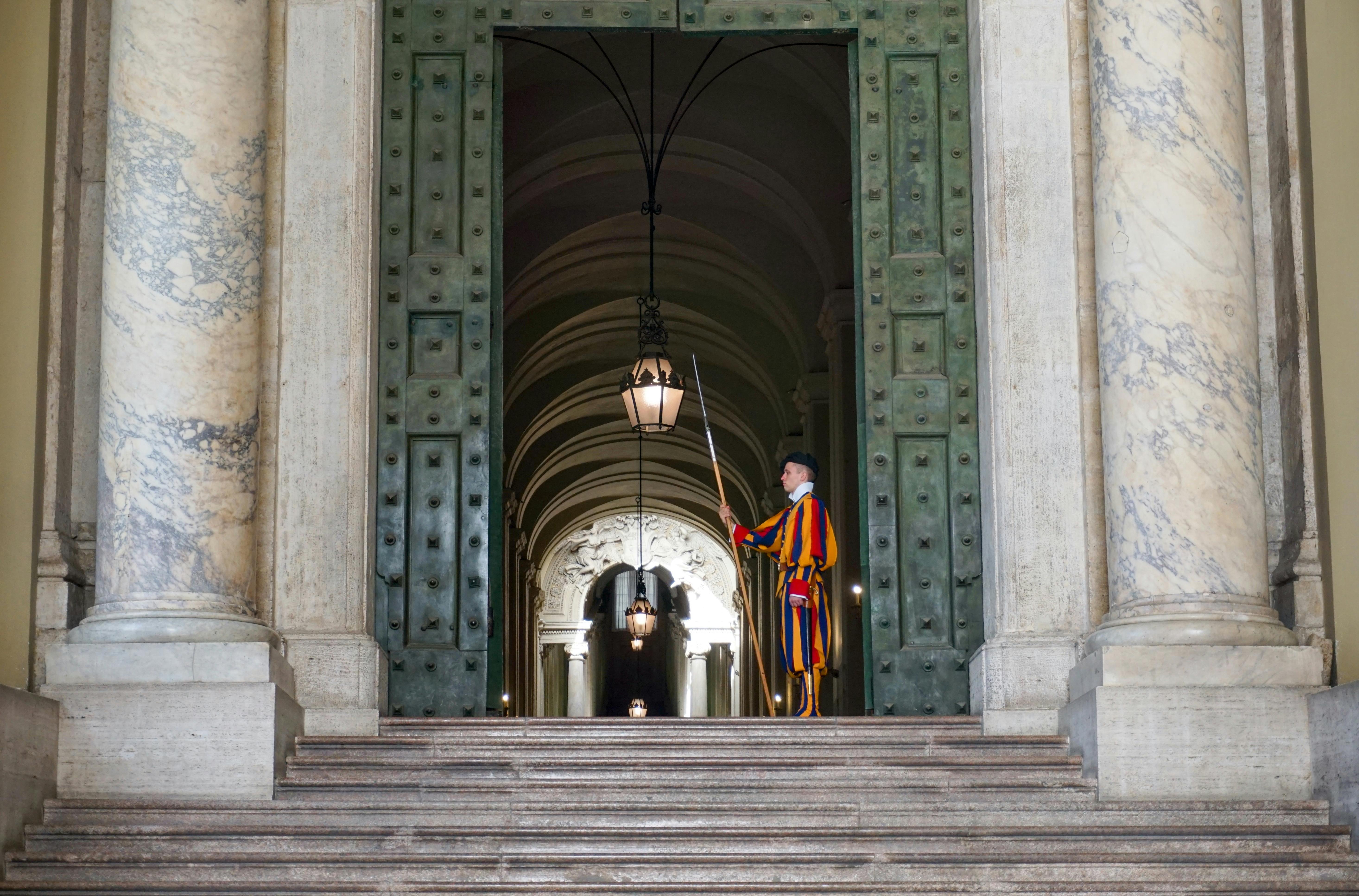 ingyenes Vatikáni svájci gárda áll a nagy bejáratnál, hagyományos színes öltözéket mutatva be a Vatikánban. Stockfotó
