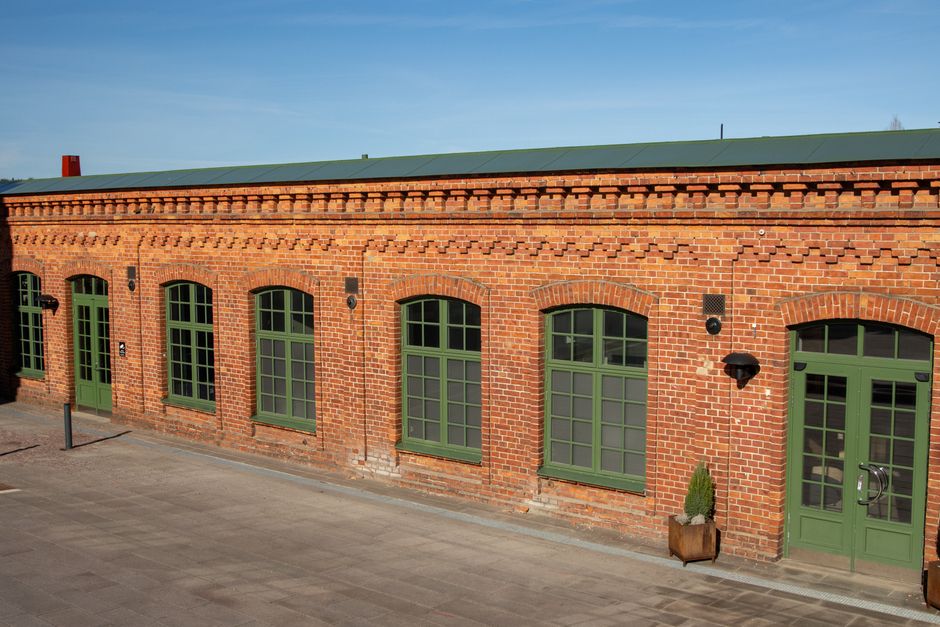 A charming red brick building with green windows in Jönköping, Sweden, under clear blue skies.