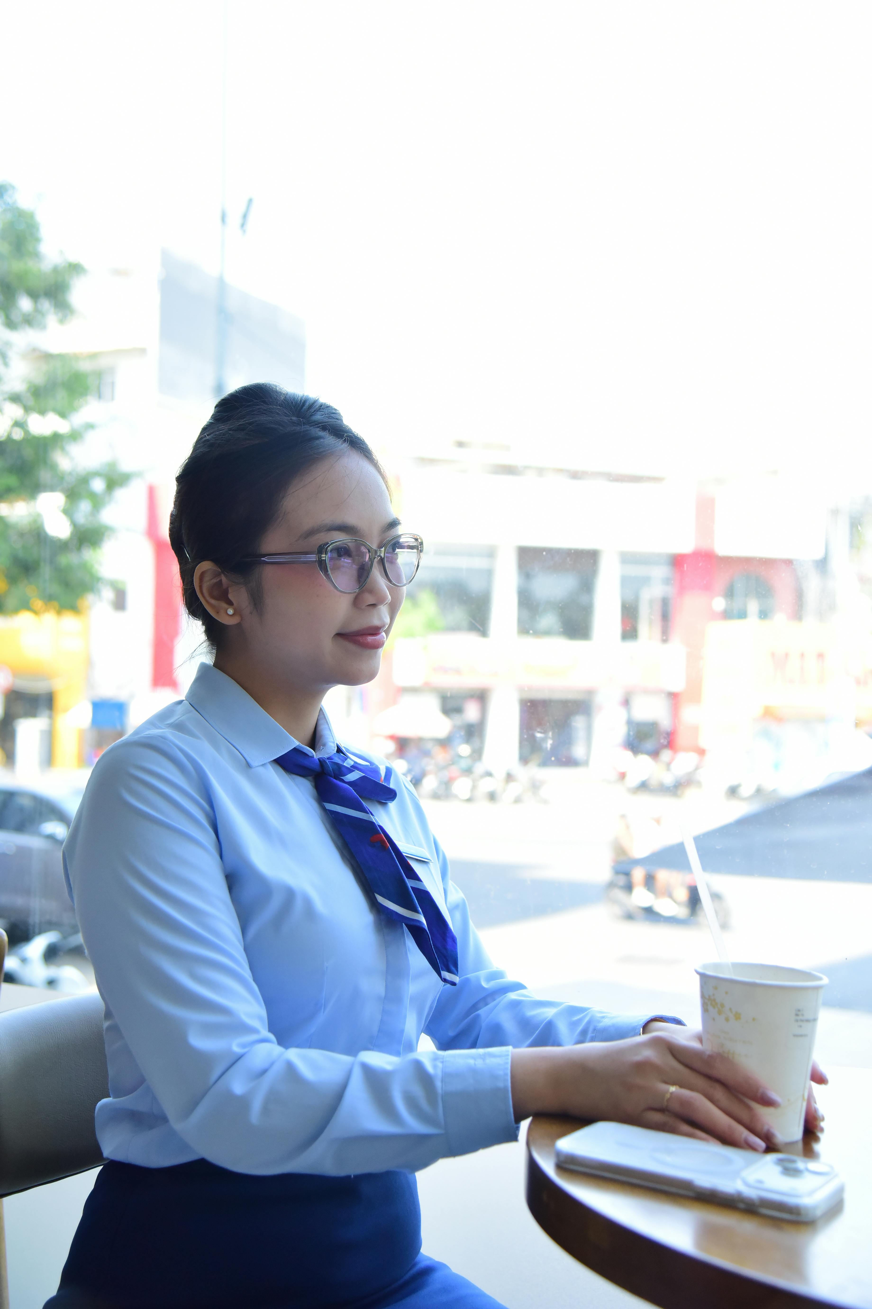 Безкоштовне Професійна молода жінка в офісному одязі сидить з чашкою кави в сучасному кафе. стокове фото