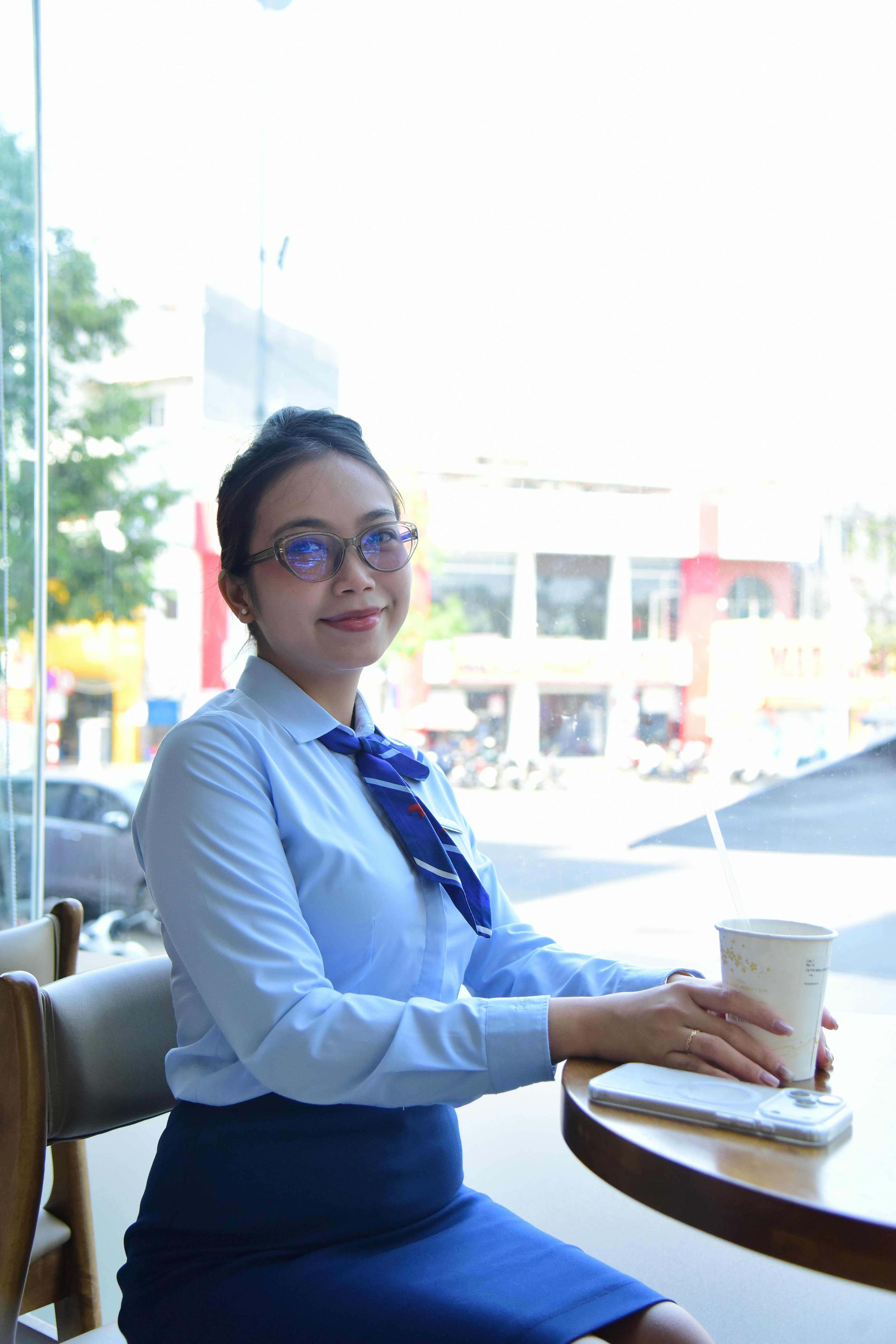 ingyenes Mosolygó üzletasszony kávézik egy kávézóban, az ablaknál ülve, városi kilátással. Stockfotó