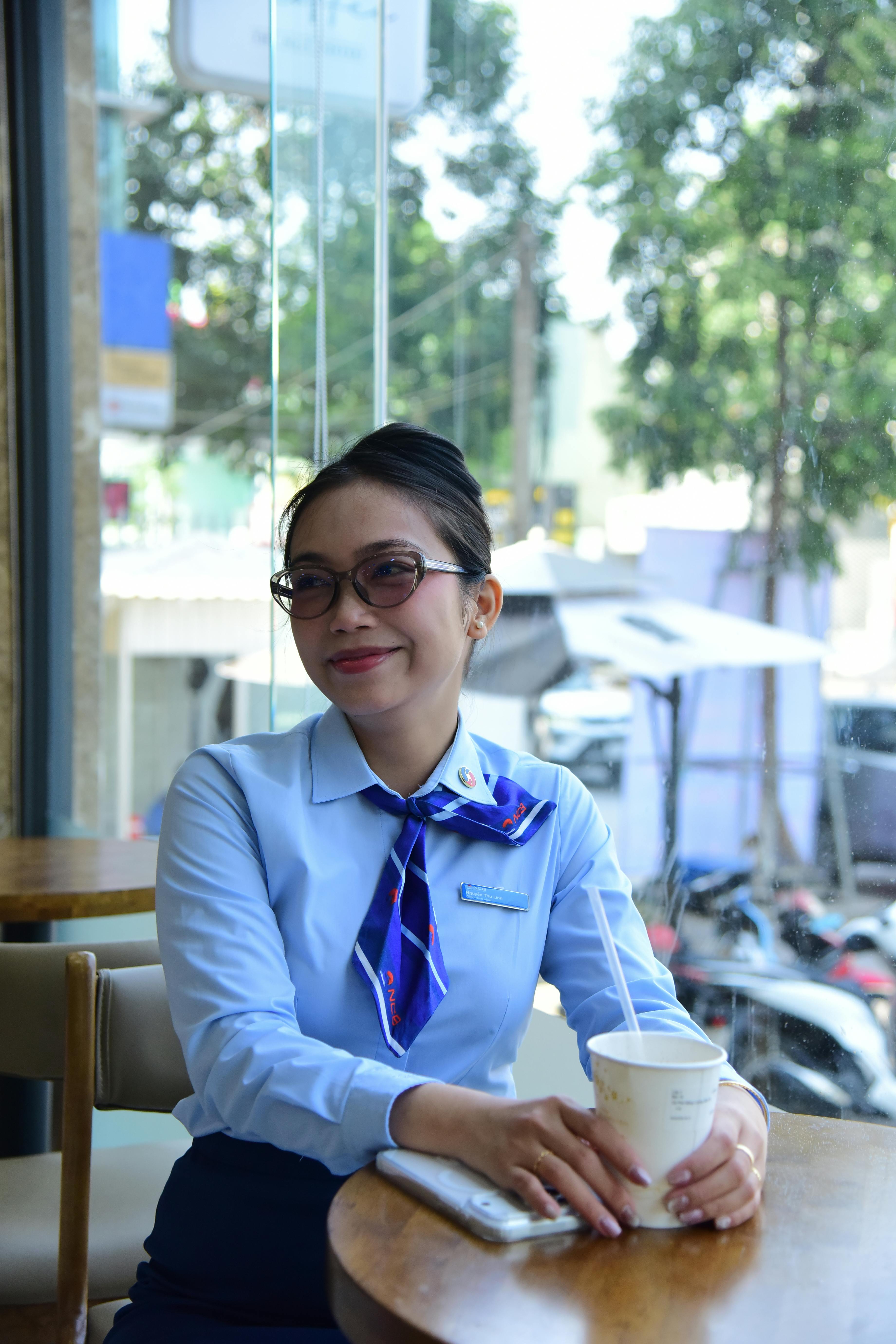 ingyenes Mosolygó nő üzleti öltözékben kávézik egy kávézóban az ablak mellett. Stockfotó