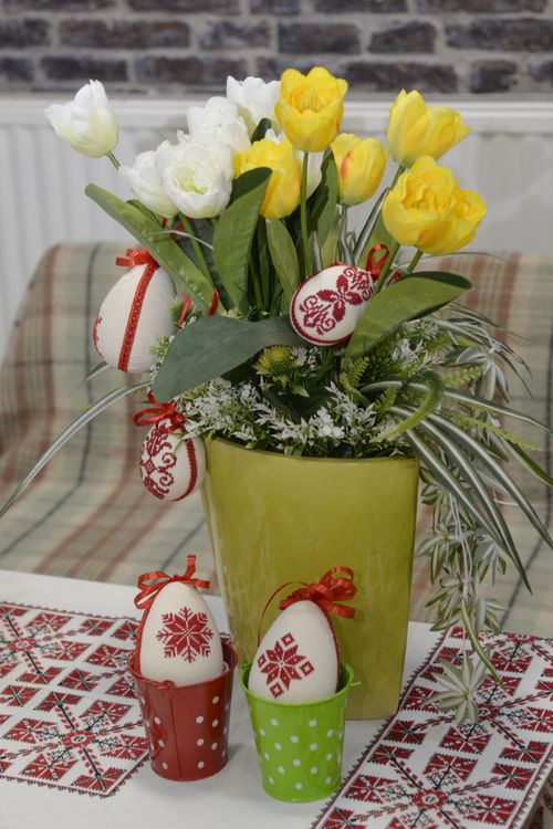 Free Vibrant yellow and white tulip arrangement paired with traditional cross-stitched Easter eggs. Stock Photo