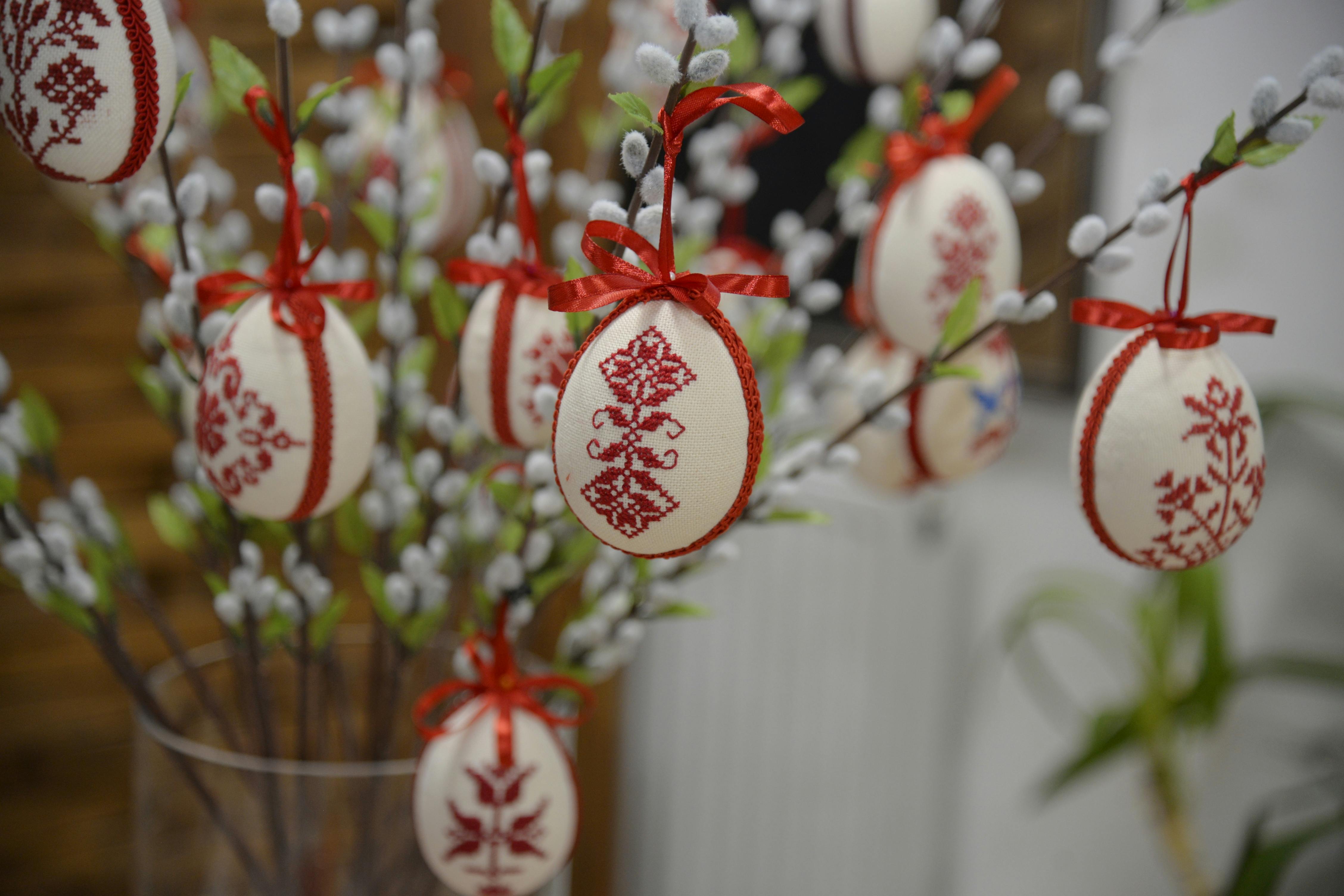 免费 色彩鲜艳的十字绣复活节彩蛋挂在室内装饰树上。 素材图片