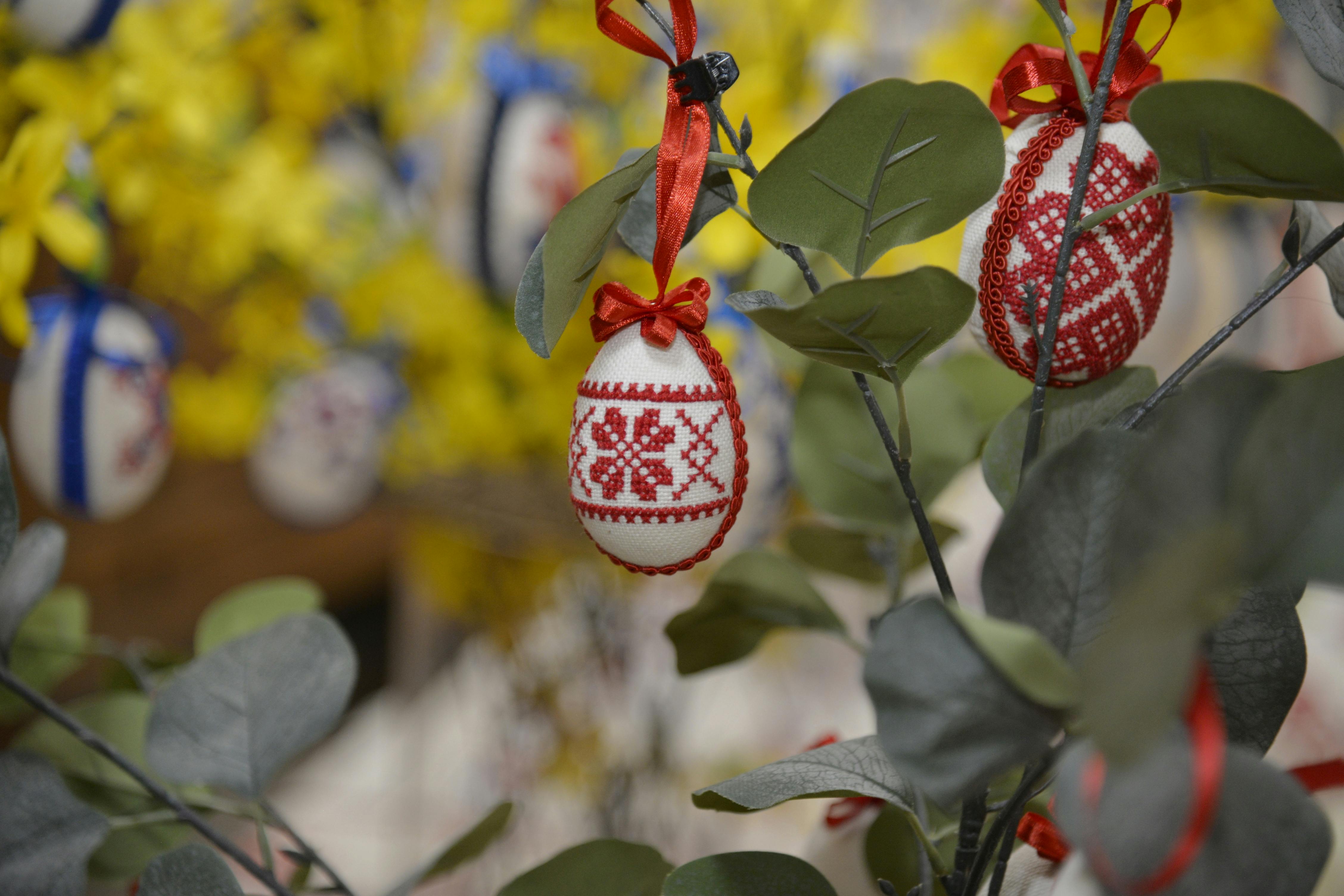 免费 春天，色彩鲜艳的复活节彩蛋，上面绣着十字绣图案，挂在装饰树上。 素材图片