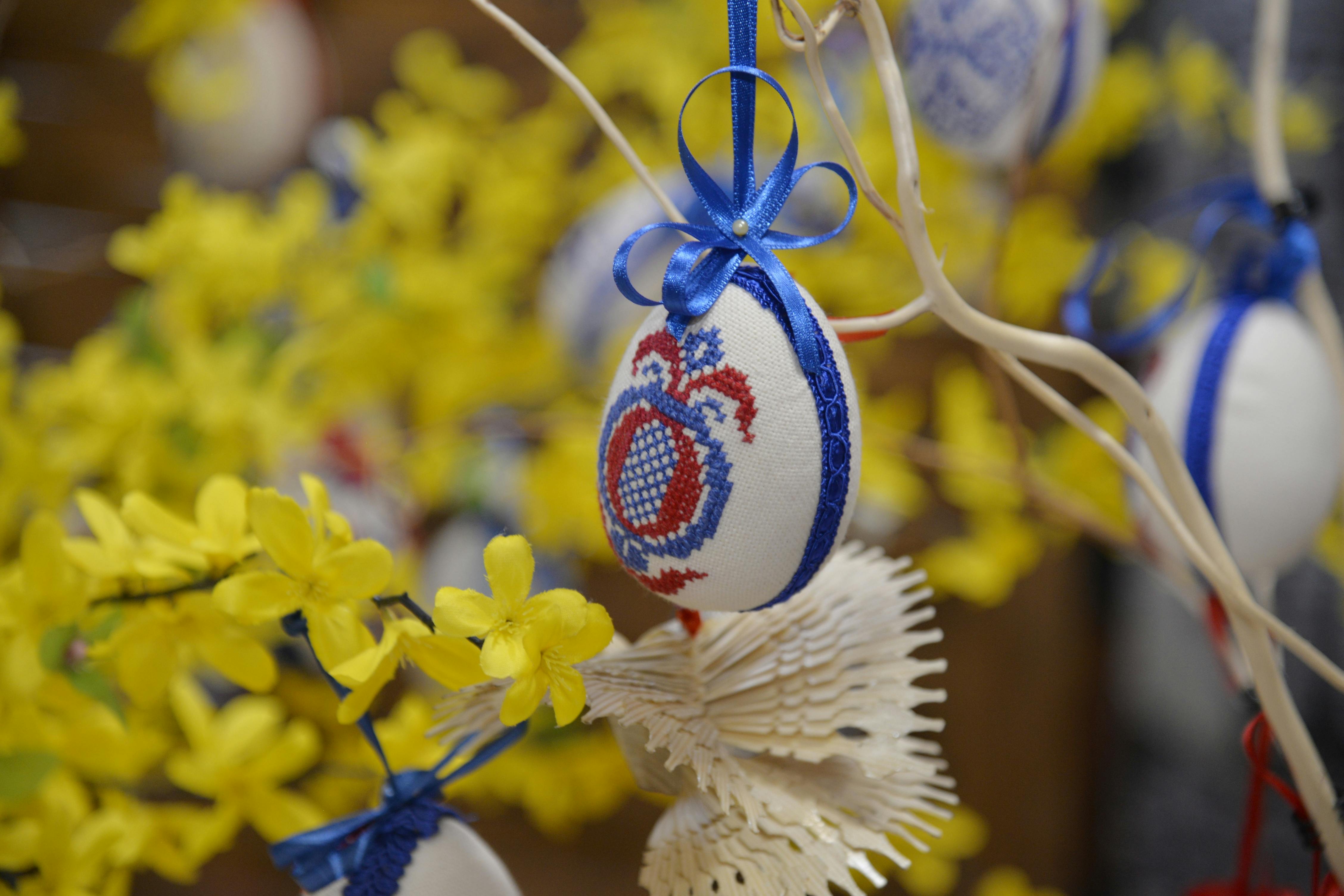 免费 在匈牙利瓦萨罗斯纳梅尼，色彩缤纷的十字绣复活节彩蛋悬挂在开满明亮黄色花朵的树枝上。 素材图片