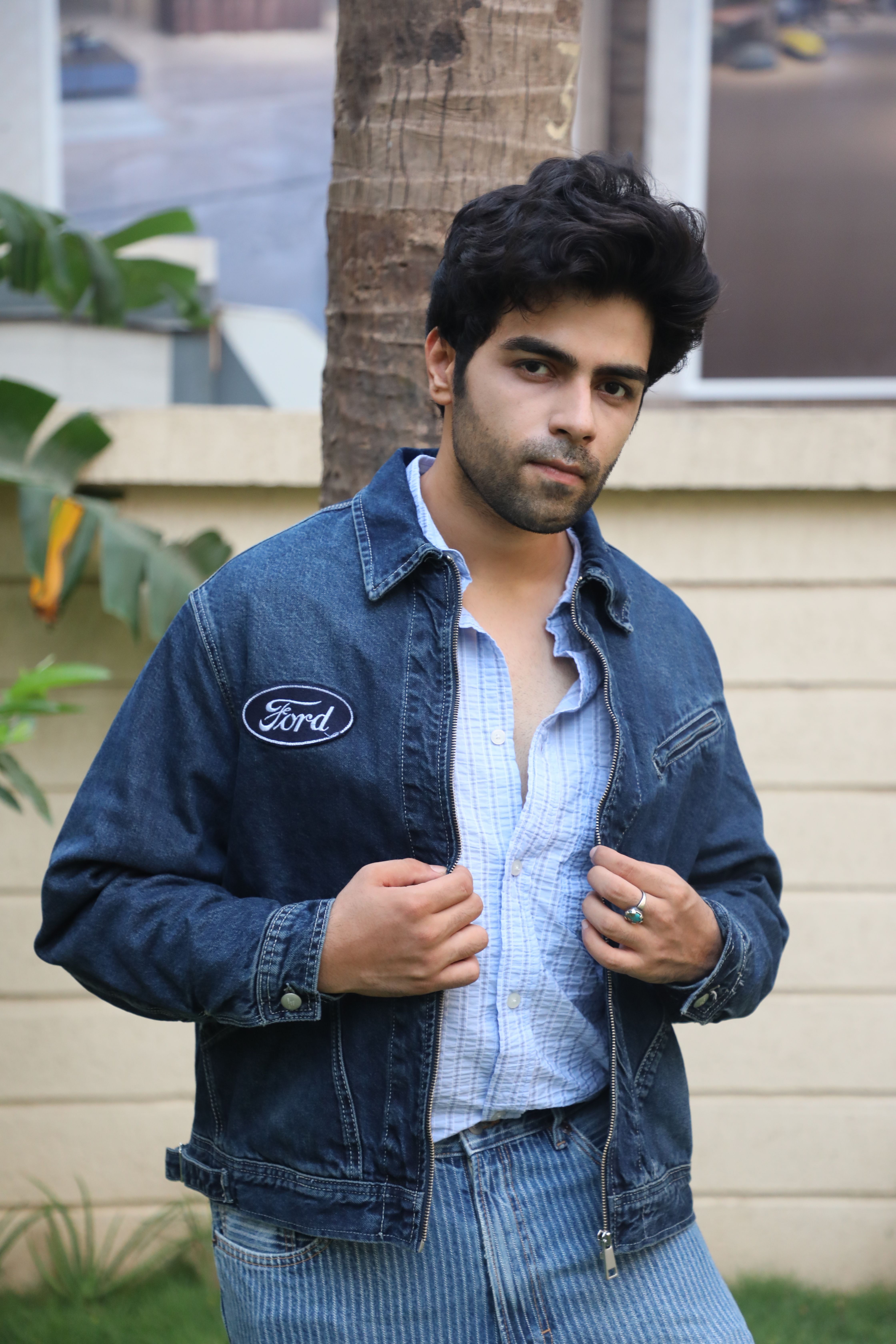 Young man modeling a denim jacket with casual style outdoors.