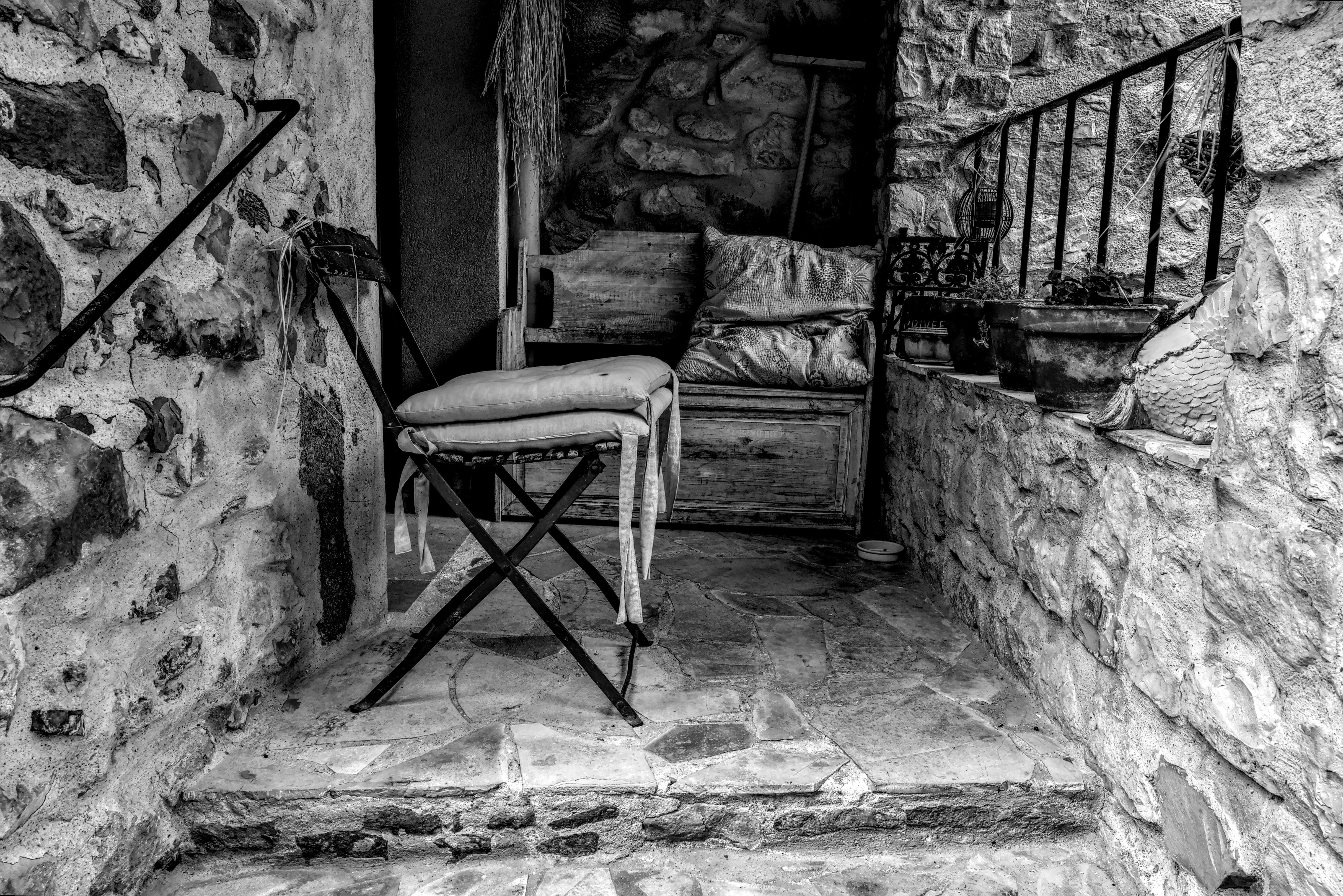 Безкоштовне Сільський кам'яний ґанок зі старовинним стільцем, знятий у чорно-білому кольорі в мальовничому французькому селі. стокове фото