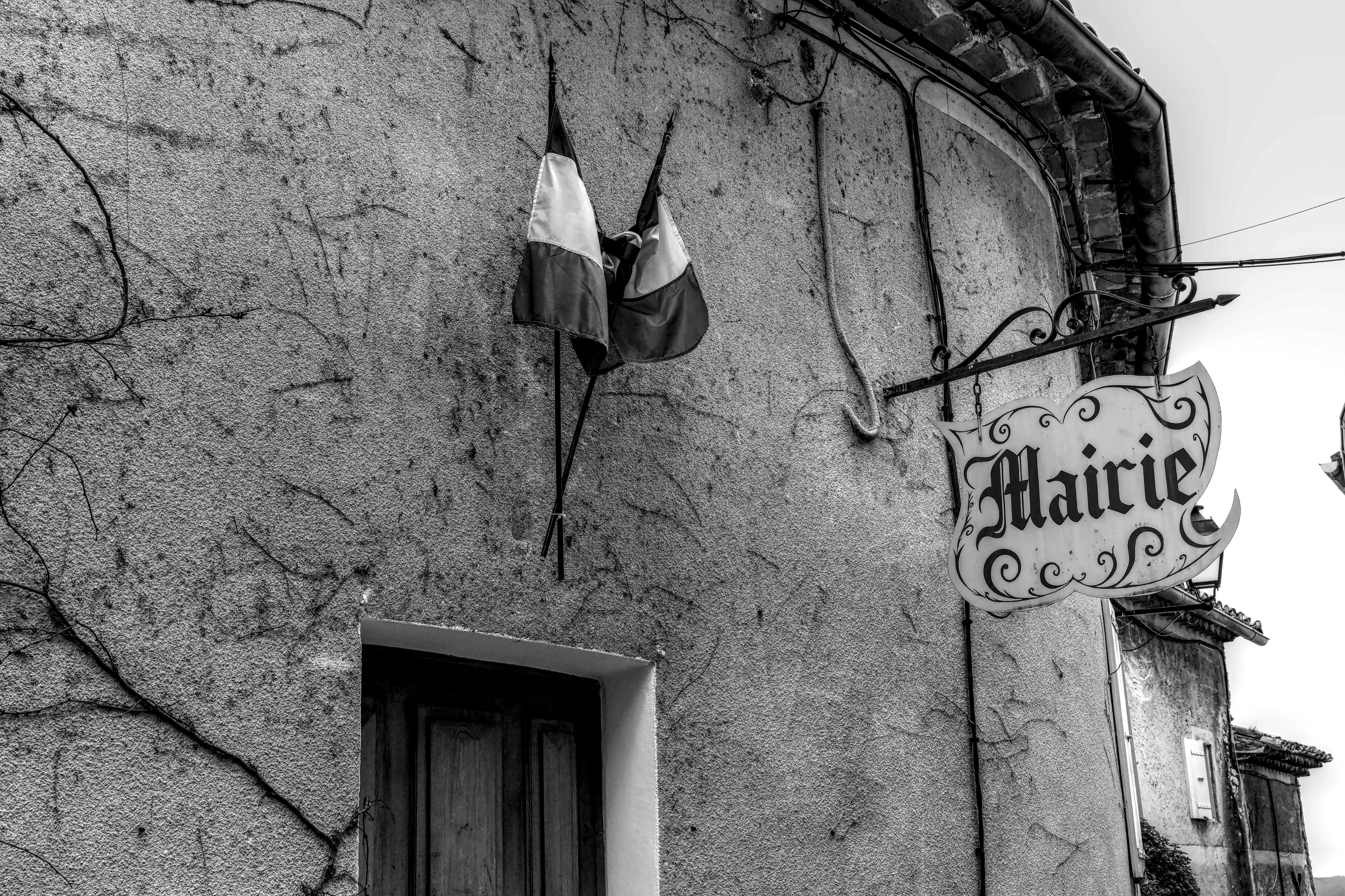 ingyenes Fekete-fehér fotó egy francia kori épület homlokzatáról zászlókkal és nosztalgikus bájjal. Stockfotó