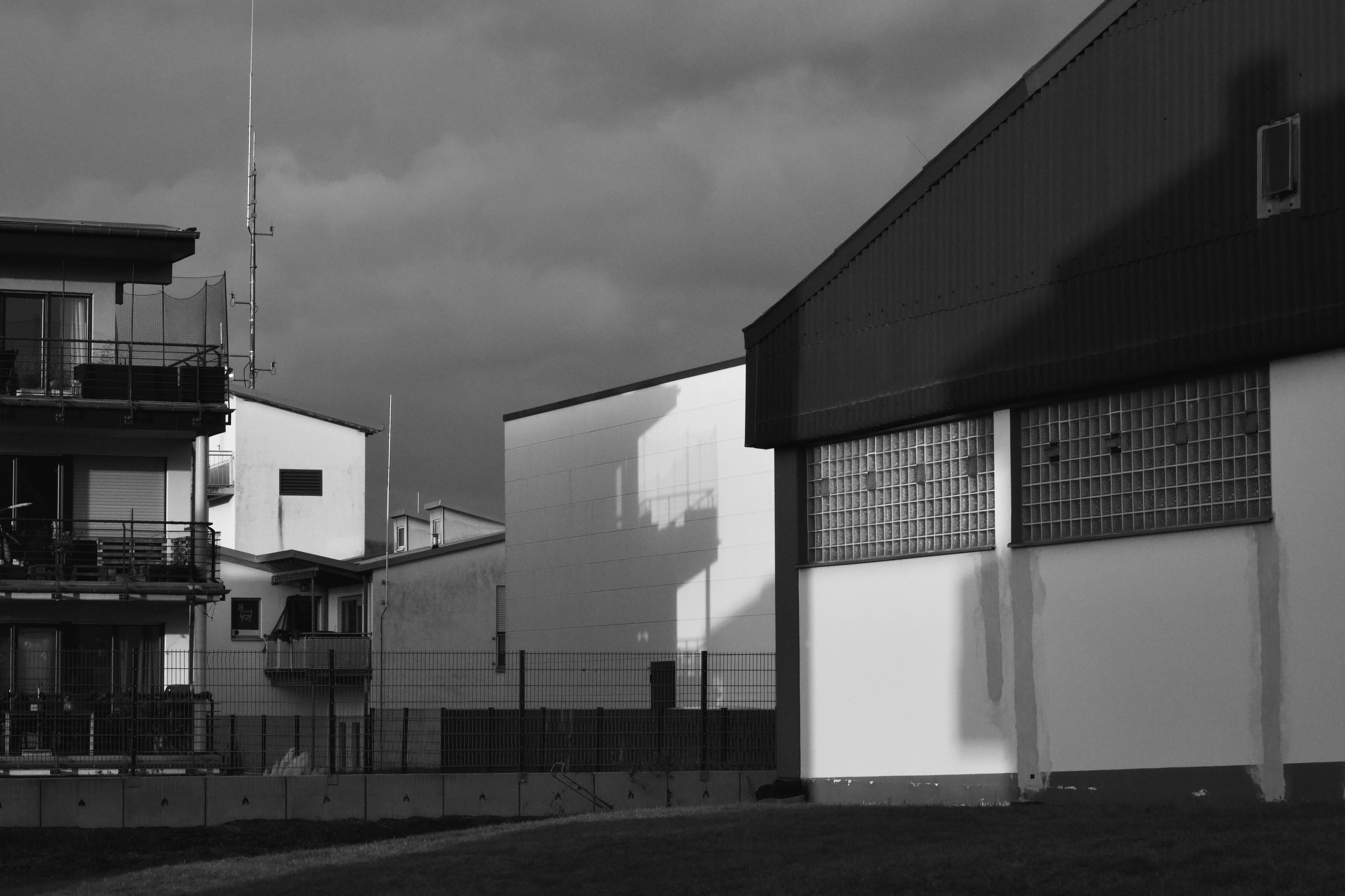 ingyenes Fekete-fehér fotó, amely városi építészetet ábrázol drámai árnyékokkal és hangulatos égbolttal. Stockfotó