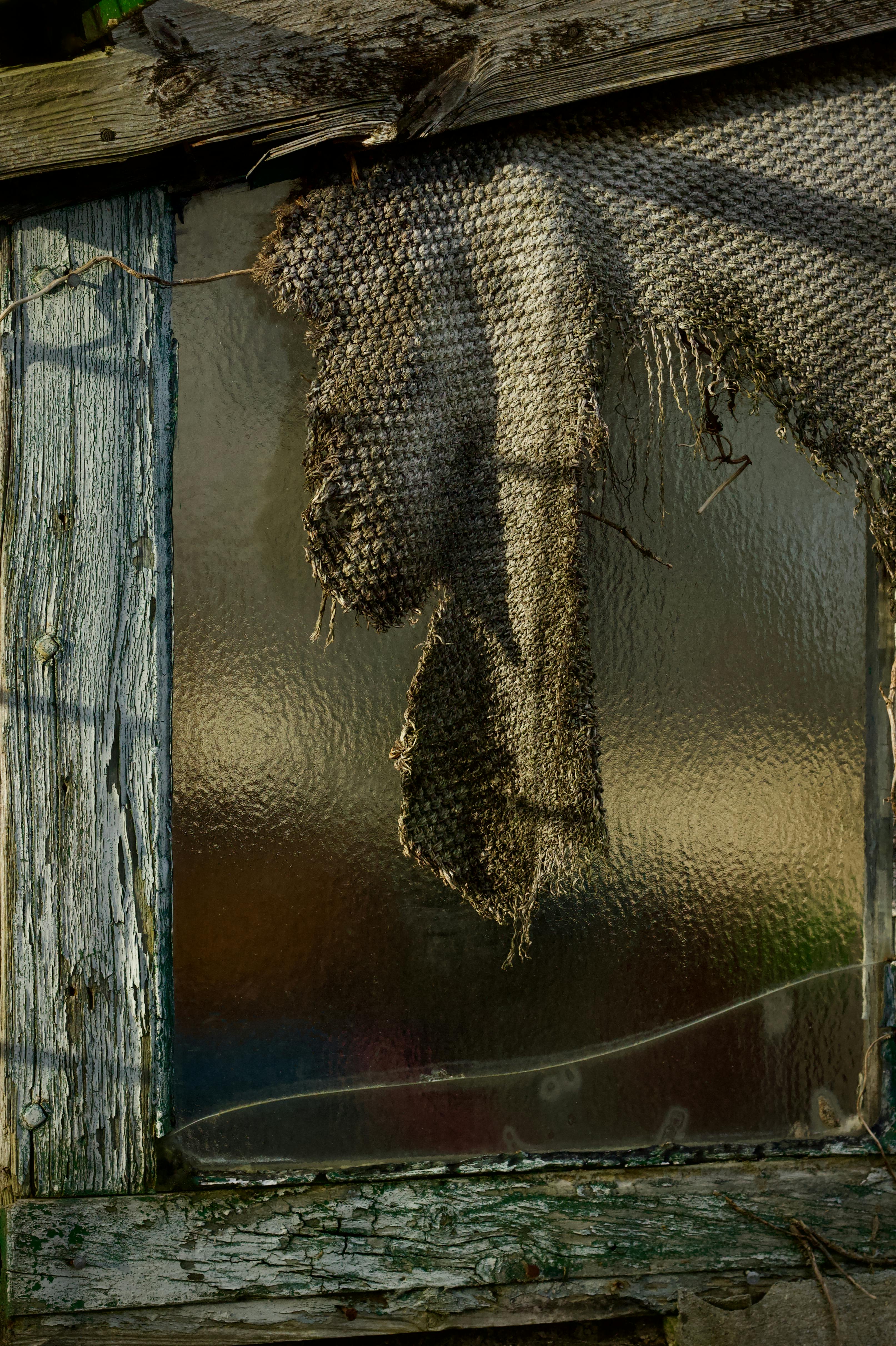 免費 一扇古樸的窗戶上掛著一塊破舊的布，讓人聯想到衰敗和懷舊的情緒。 圖庫相片