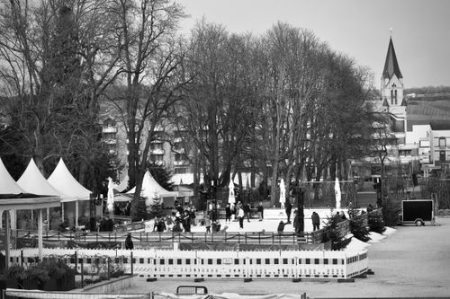 Free Black and white image of a lively outdoor ice rink with skaters in a winter setting. Stock Photo