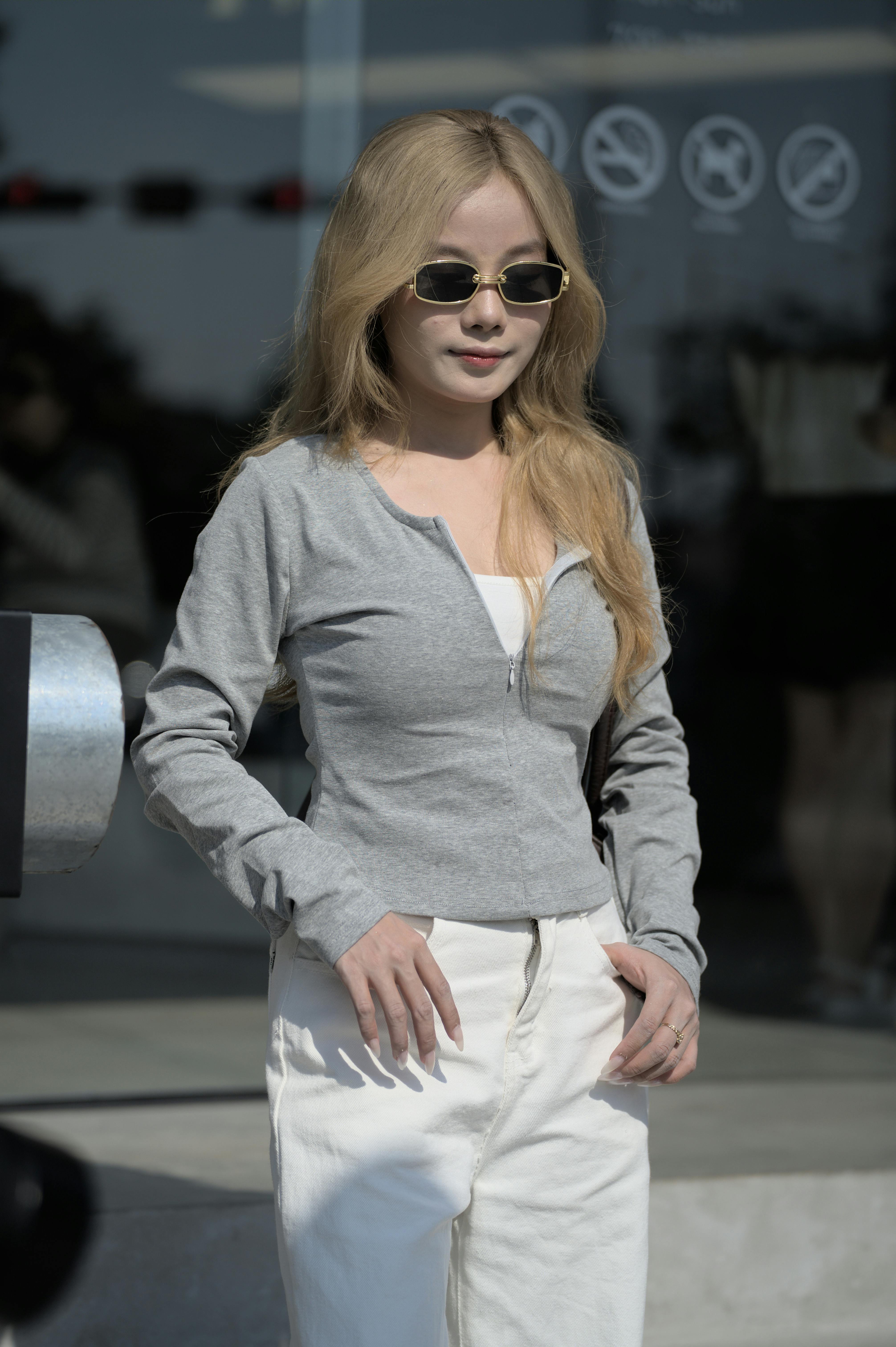 Young woman wearing sunglasses in a casual urban environment, exuding a modern fashion vibe.