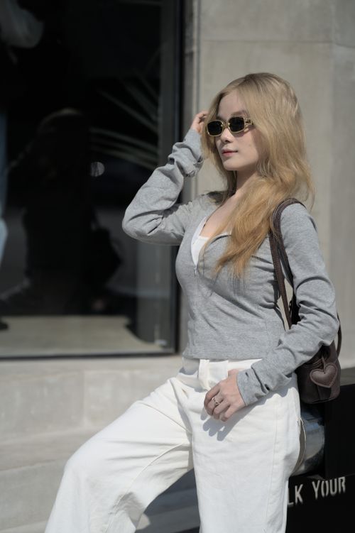 Free Stylish woman in sunglasses poses with confident expression outdoors against urban background. Stock Photo