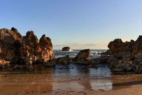 Free Tranquil sunset view of rocky coastline at a beach in Llanes, Spain. Stock Photo