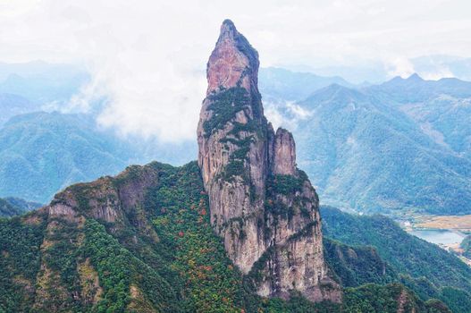 A striking view of towering rock formations amidst lush greenery and distant mountains.