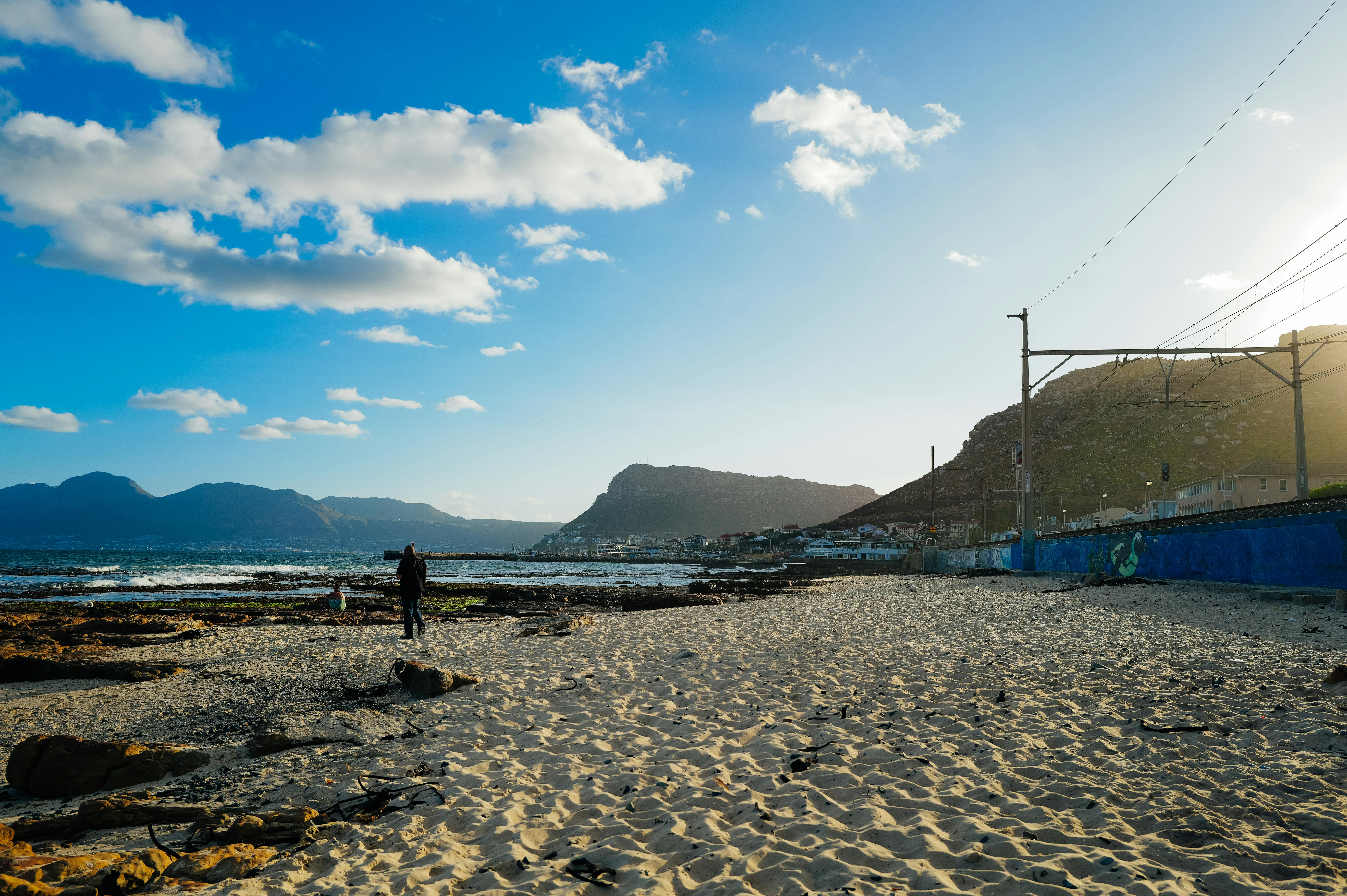 A peaceful beach scene with people strolling along the shore at sunset.