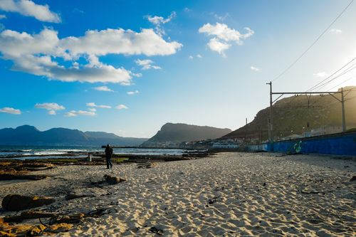 Free A peaceful beach scene with people strolling along the shore at sunset. Stock Photo