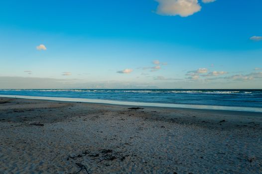 Peaceful beach with gentle ocean waves under a bright blue sky, perfect for relaxation.