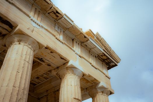 Detailed view of the Parthenon with classical Doric columns under a cloudy sky.