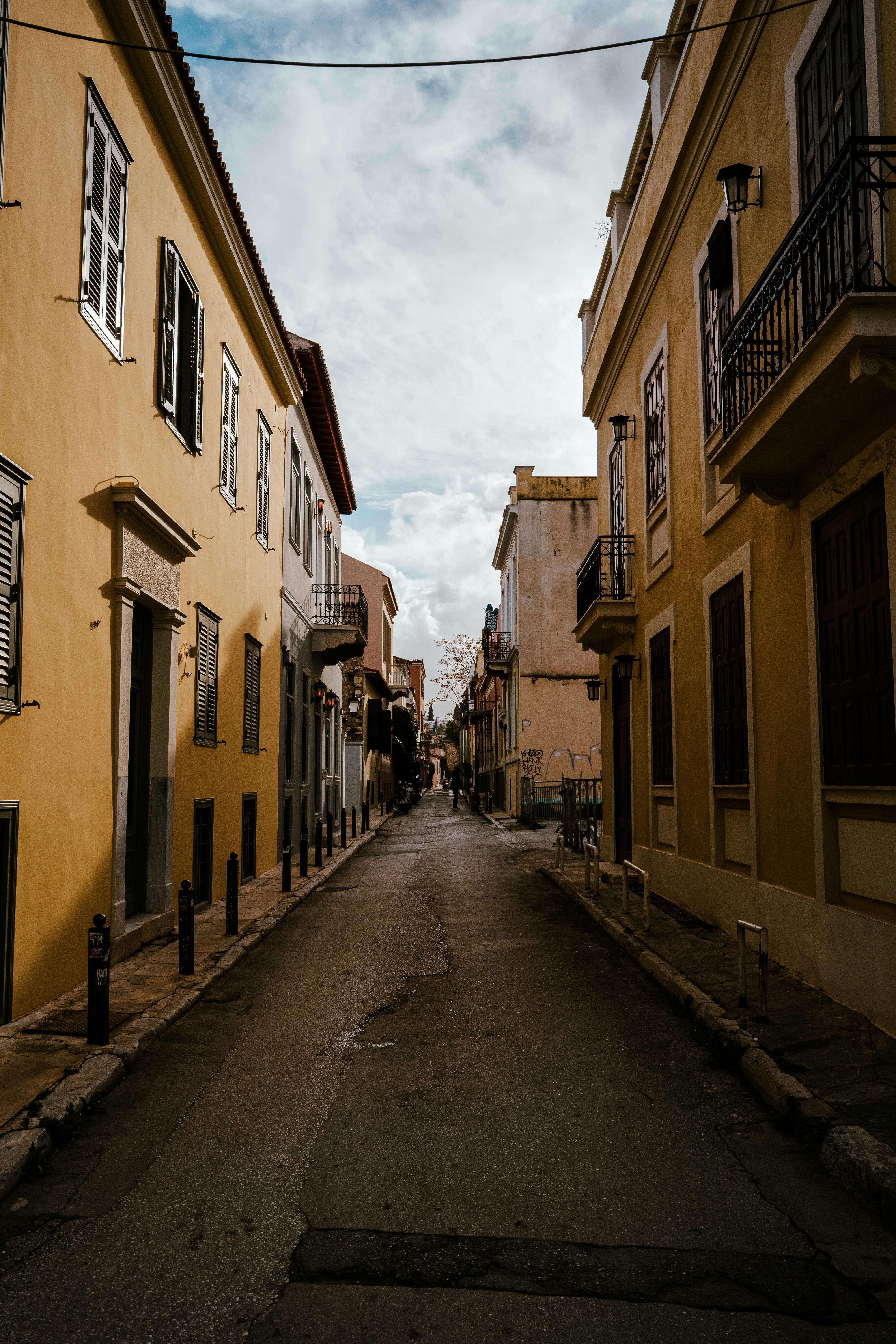 ฟรี ถนนแคบๆ ที่เรียงรายไปด้วยอาคารเก่าแก่สีสันสดใส ภายใต้ท้องฟ้าที่ปกคลุมไปด้วยเมฆ สะท้อนให้เห็นถึงเสน่ห์แบบยุโรปที่คงอยู่ตลอดกาล คลังภาพถ่าย