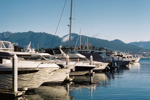 Discover tranquility at Vancouver's Coal Harbour with yachts and mountain views reflecting in calm waters.