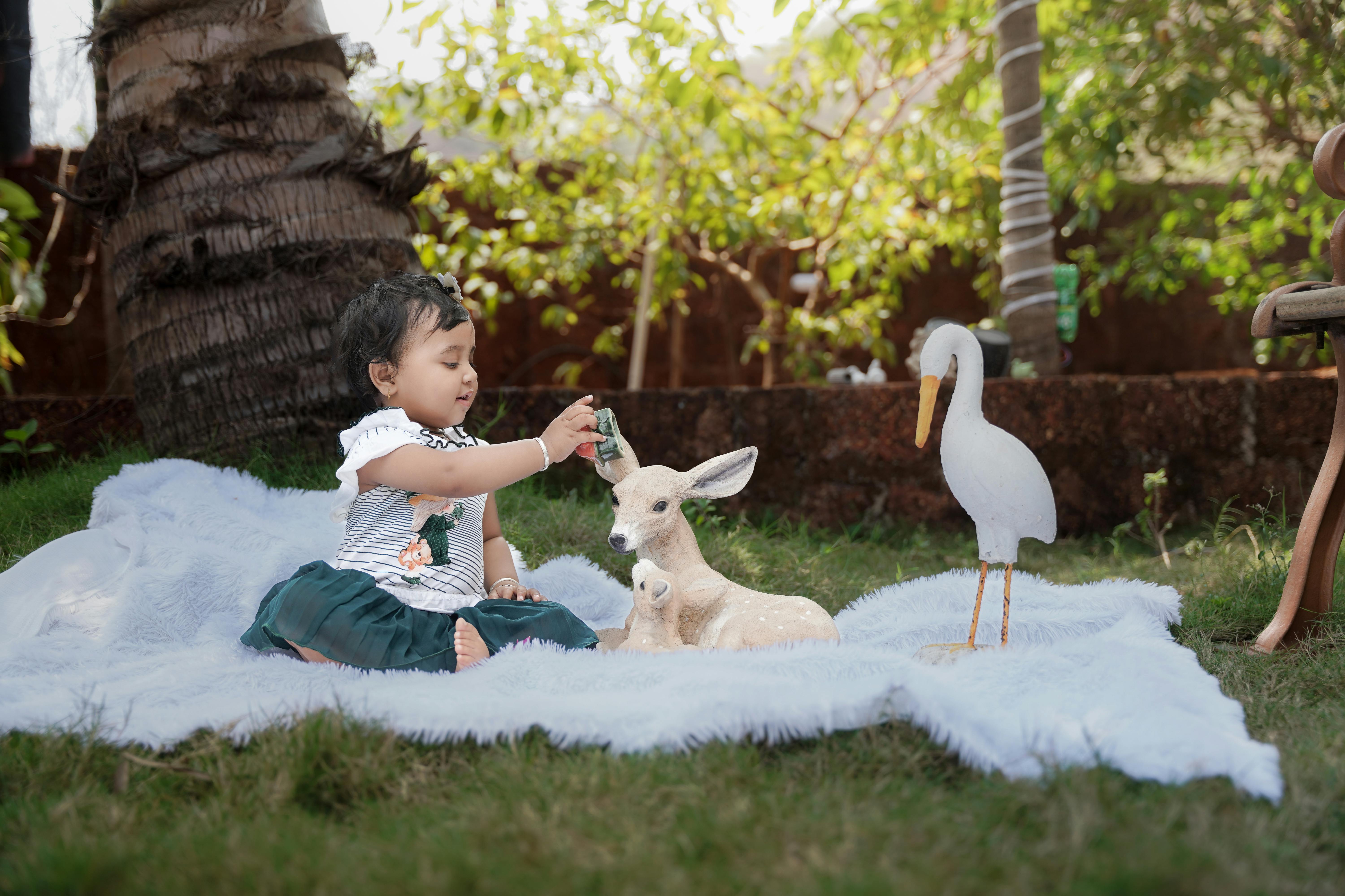 ingyenes Egy kisgyermek játékszarvassal és -madárral játszik egy napsütéses napon a szabadban. Stockfotó