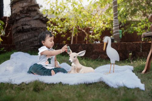 Free A toddler plays with a toy deer and bird on a sunny day outdoors. Stock Photo