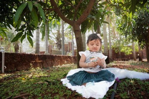 Free A baby girl enjoying her time under lush mango trees, playing with nature. Stock Photo