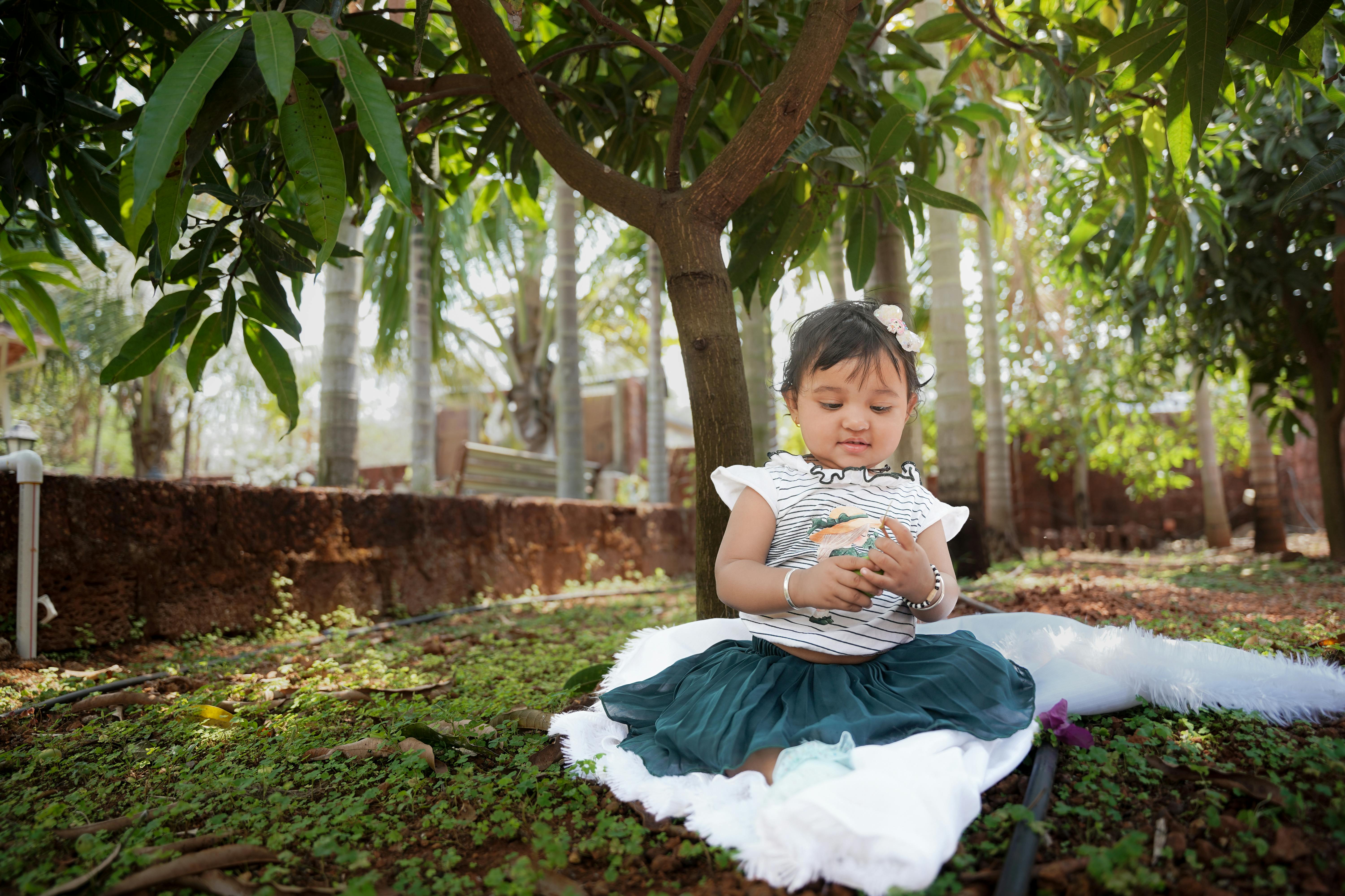 Zadarmo Dievčatko si užíva čas pod bujnými mangovníkmi a hrá sa s prírodou. Fotka z fotobanky