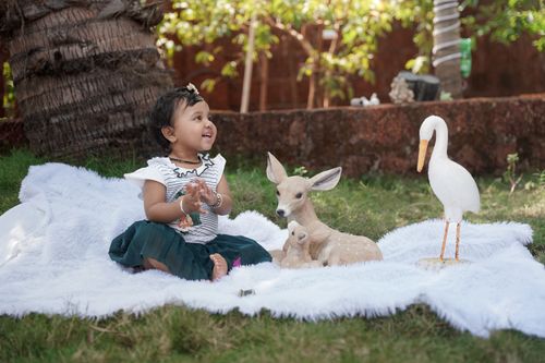 Free A child enjoys outdoor playtime with deer and stork figurines, surrounded by nature. Stock Photo