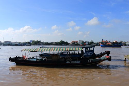 Free A traditional boat floats on the scenic Mekong River in Vietnam under a clear blue sky. Stock Photo