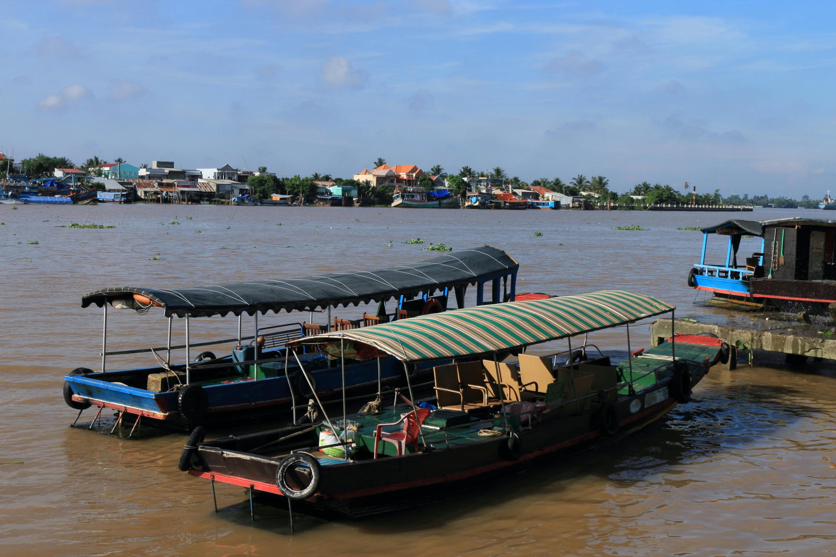 Zadarmo Tradičné drevené lode zakotvené pri rieke vo Vietname pod jasnou modrou oblohou. Fotka z fotobanky