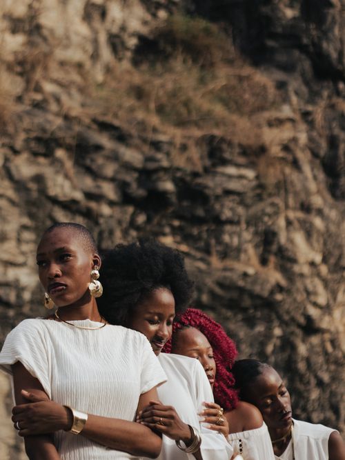 Free A group of women in white clothing stands elegantly against a rocky backdrop, showcasing unity and strength. Stock Photo