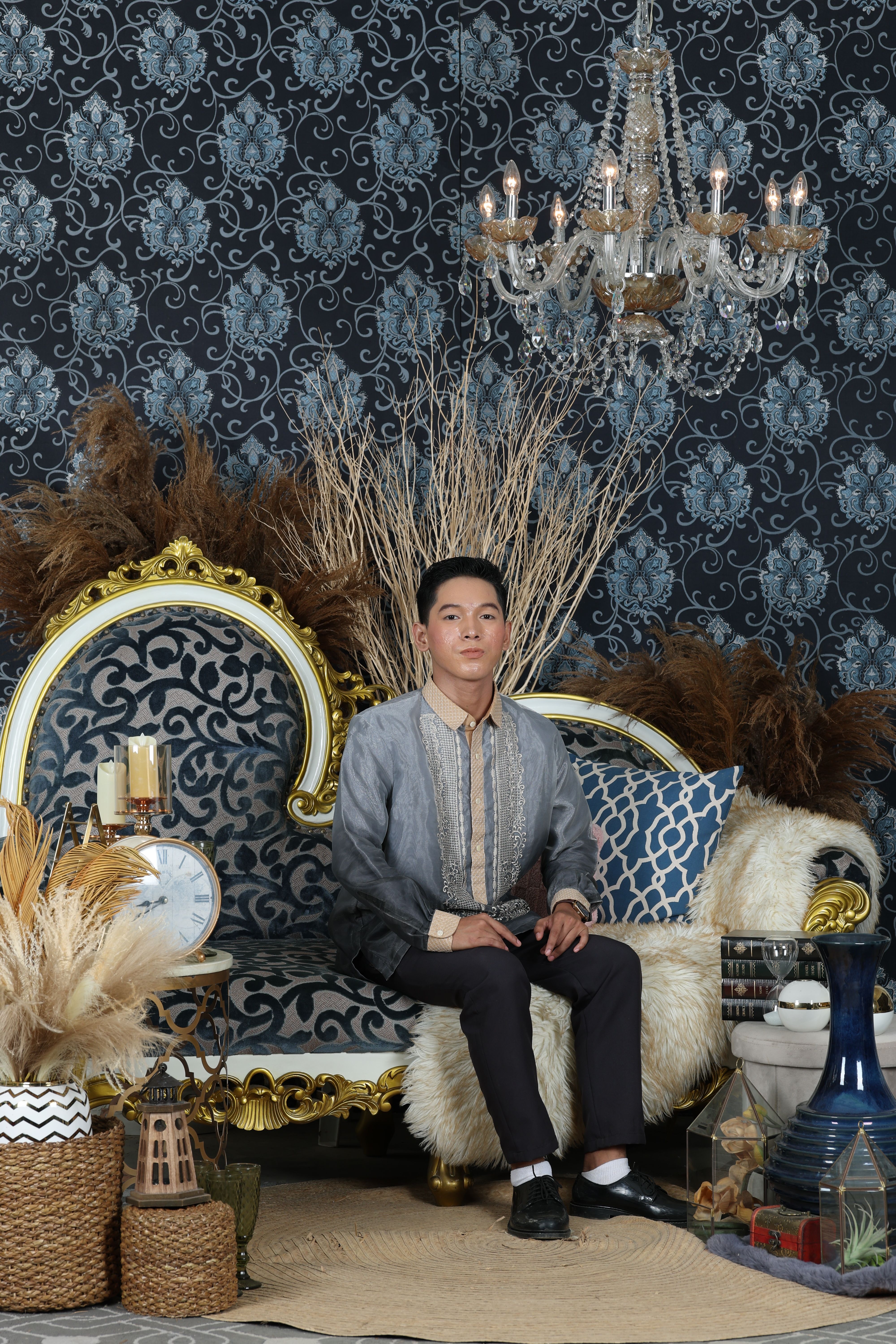 Young man in traditional attire seated in a luxurious vintage room.