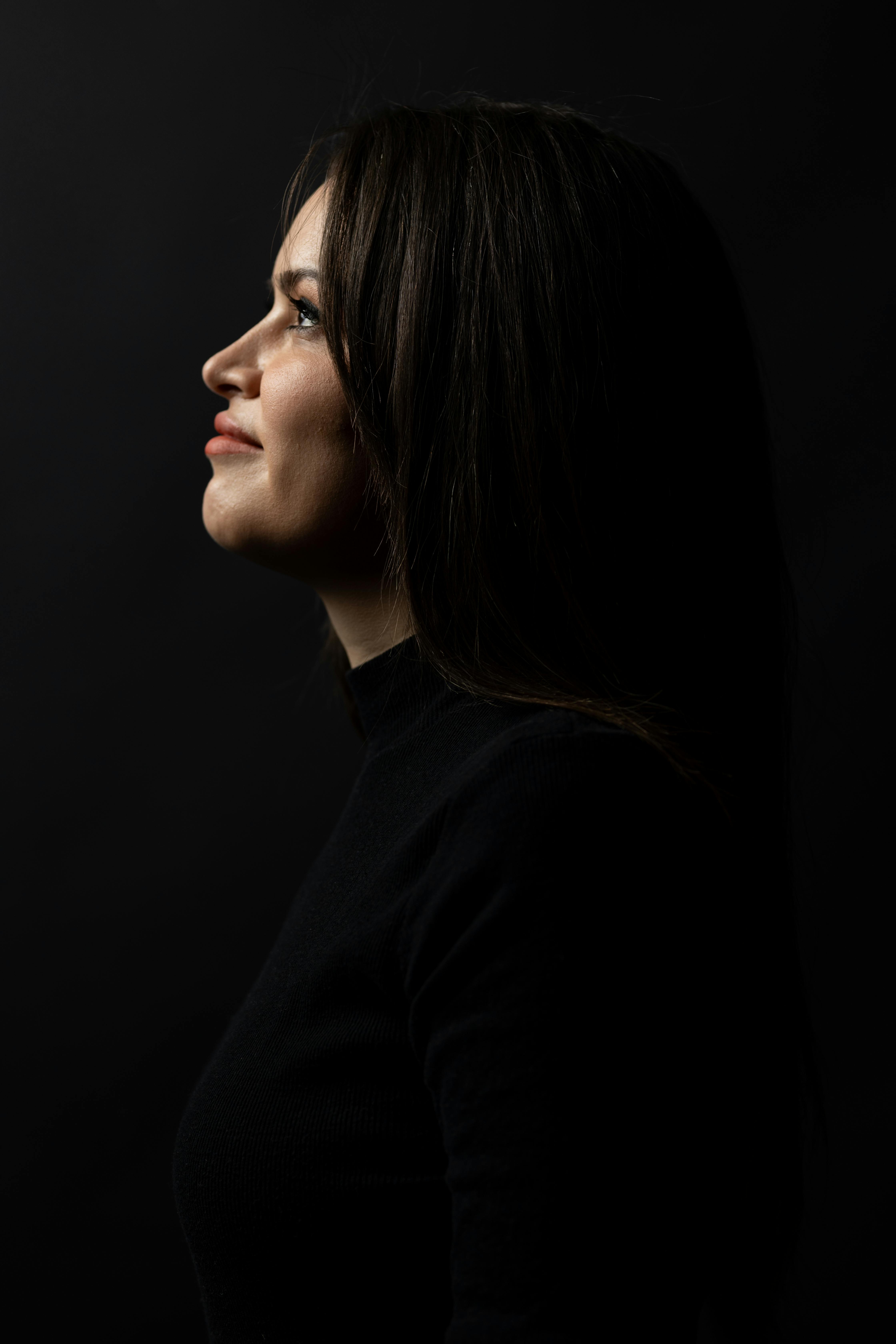 A stylish side profile of a woman in dramatic lighting on a dark background.