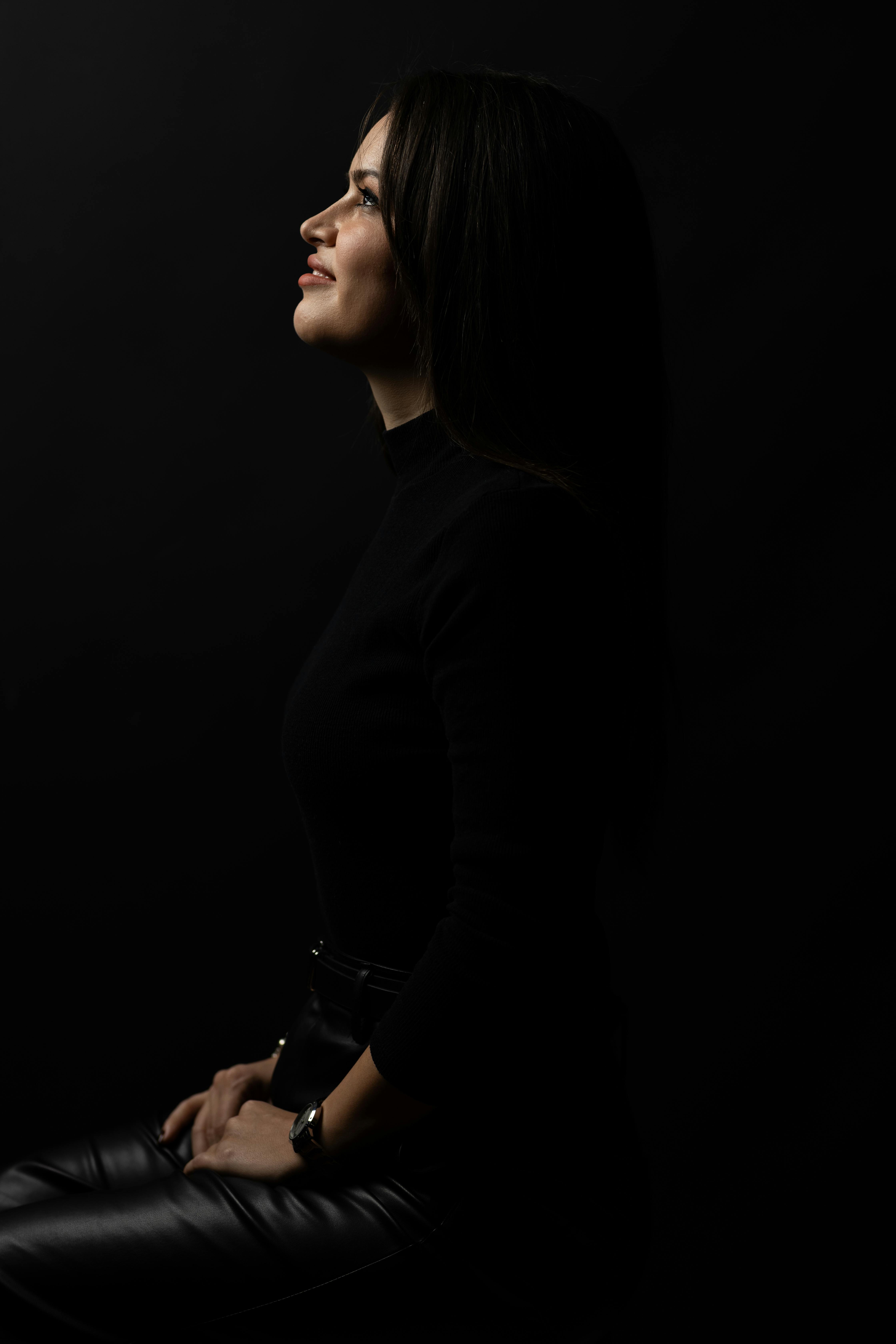 Striking side profile portrait of a woman in low light, exuding elegance and sophistication.