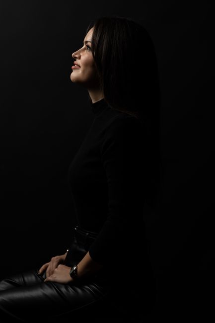 Striking side profile portrait of a woman in low light, exuding elegance and sophistication.