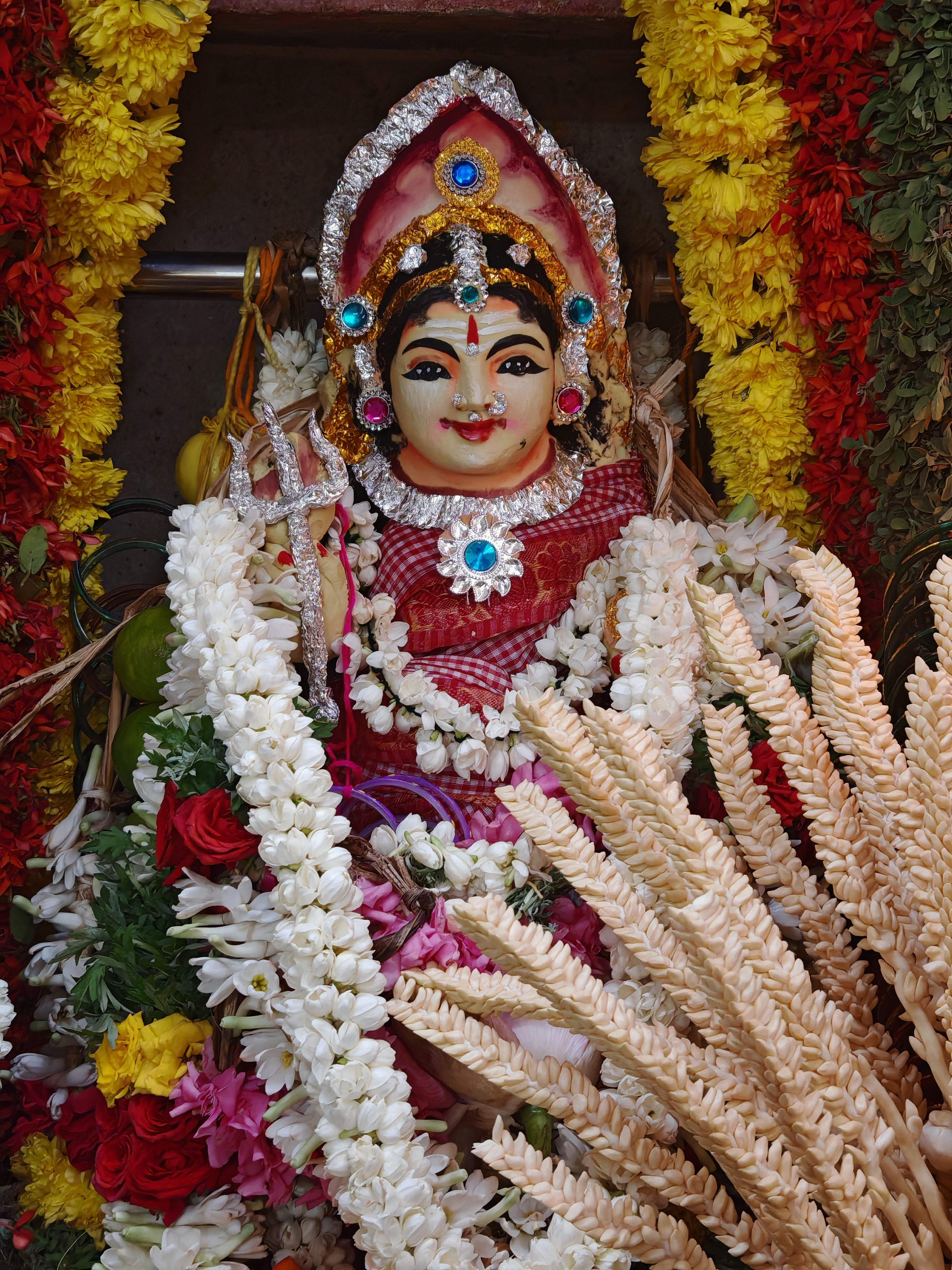 Vibrant image of a decorated Hindu goddess idol surrounded by flowers in Sivakasi, India.