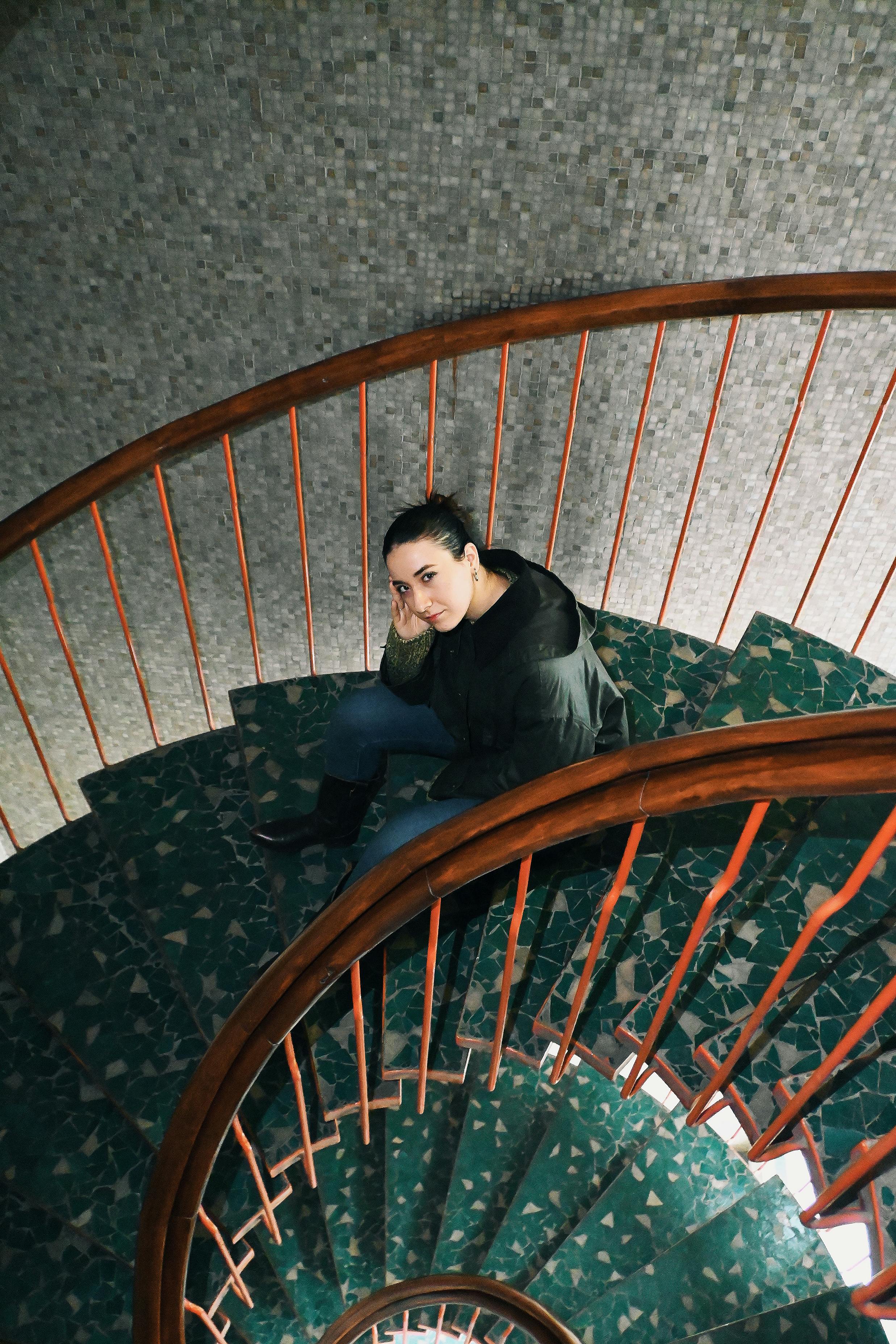 ingyenes Portré egy fiatal nőről, aki egy stílusos csigalépcsőn pihen, felülről fényképezve. Stockfotó