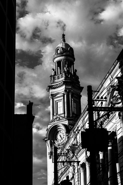 Free Black and white photo of a historic clock tower with dramatic clouds in Santos, Brazil. Stock Photo