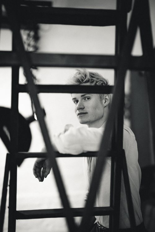 Free Black and white portrait of a man seen through a staircase, capturing a contemplative mood. Stock Photo
