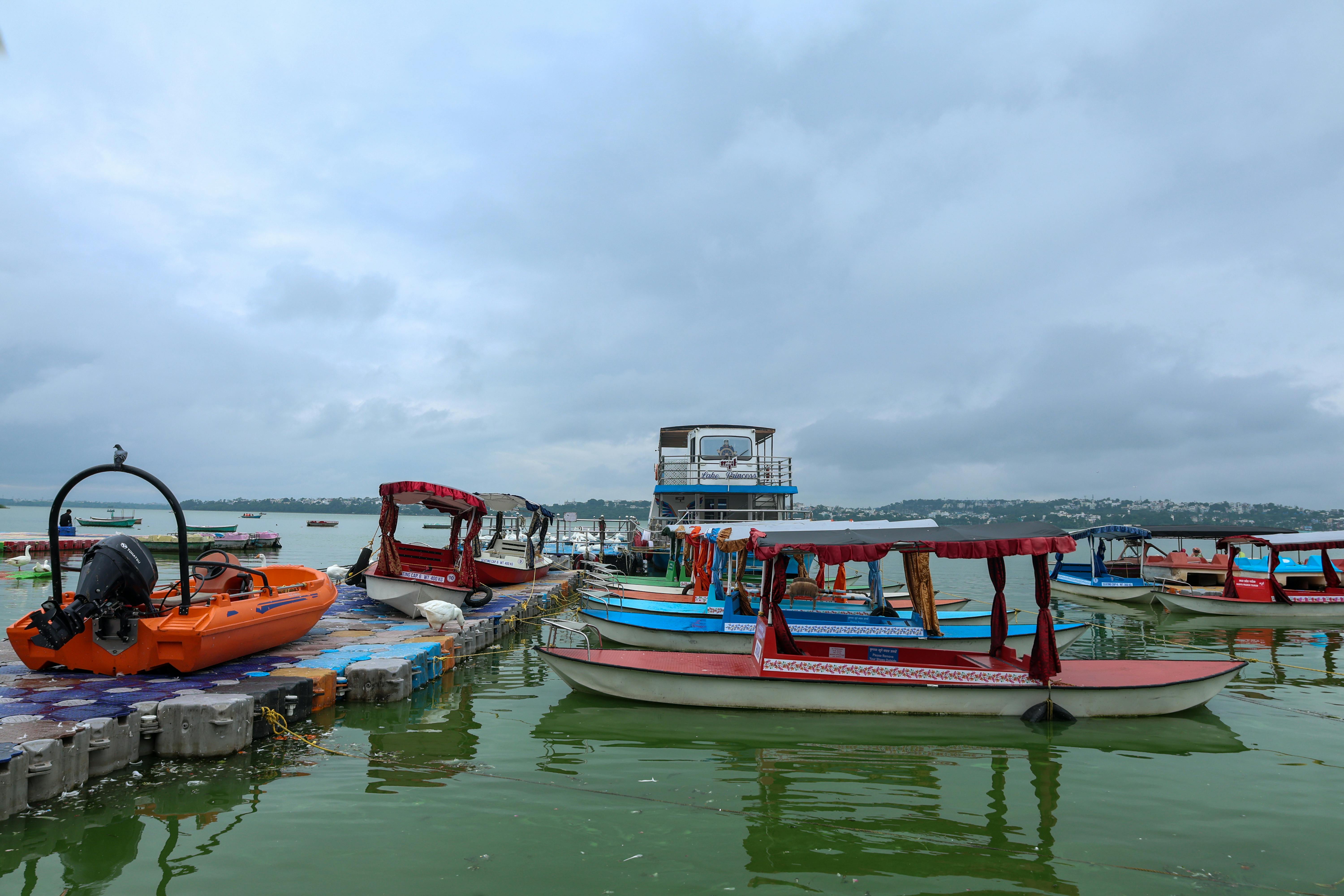Zadarmo Živé lode zakotvené na pokojnom jazere s oblačnou oblohou v pozadí, ideálne na cestovanie a voľný čas. Fotka z fotobanky