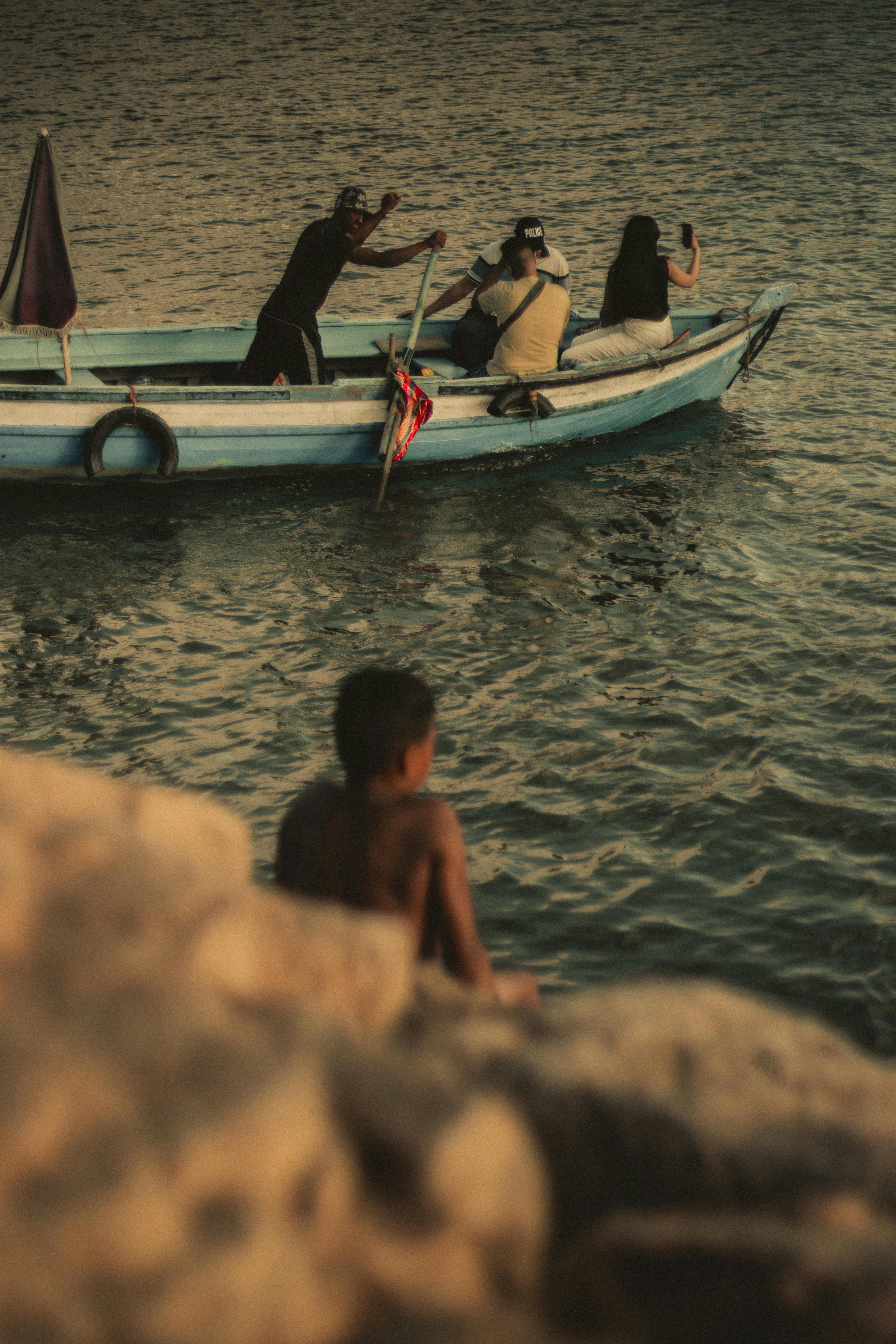 ingyenes Békés jelenet egy kis hajóról nyugodt vízen, miközben az emberek a naplementét fényképezik. Stockfotó